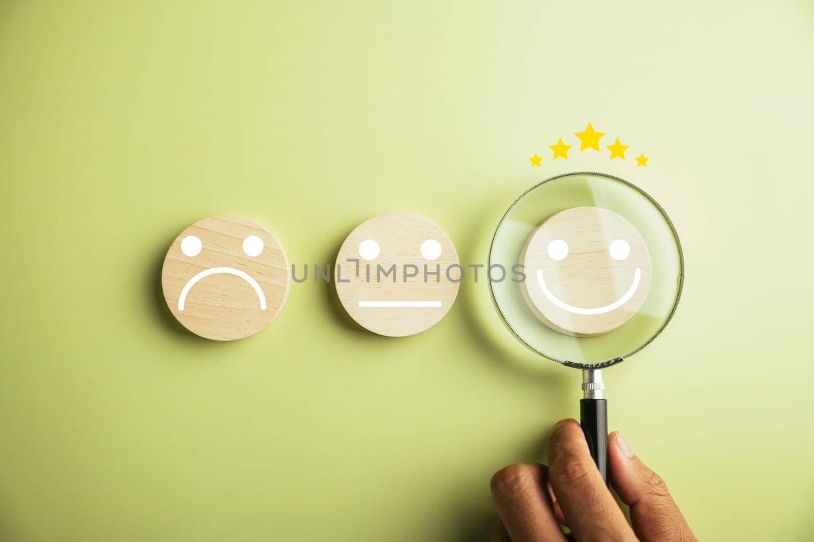 Hand holds magnifier, focusing on selected happy smiley face icon among various emotions. Good feedback rating and positive customer review. Experience, satisfaction survey, mental health.