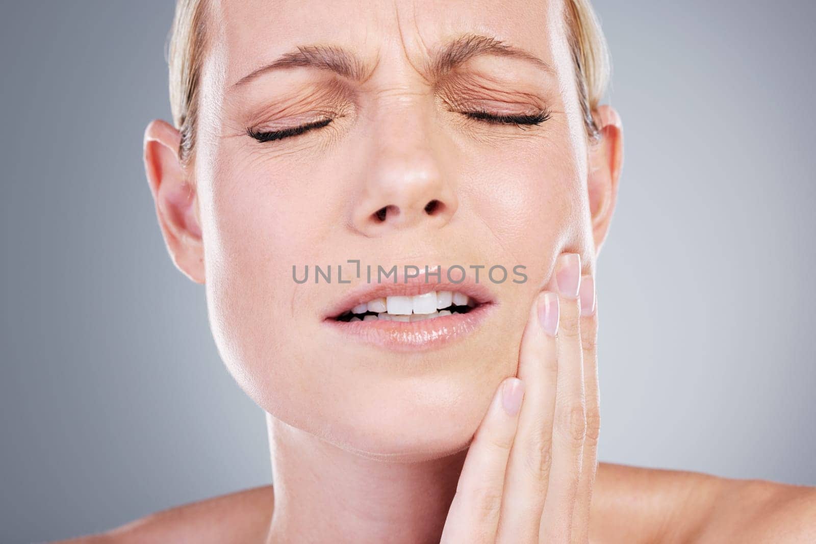 A visit to the dentist is much needed. Studio shot of an attractive mature woman experiencing toothache against a grey background