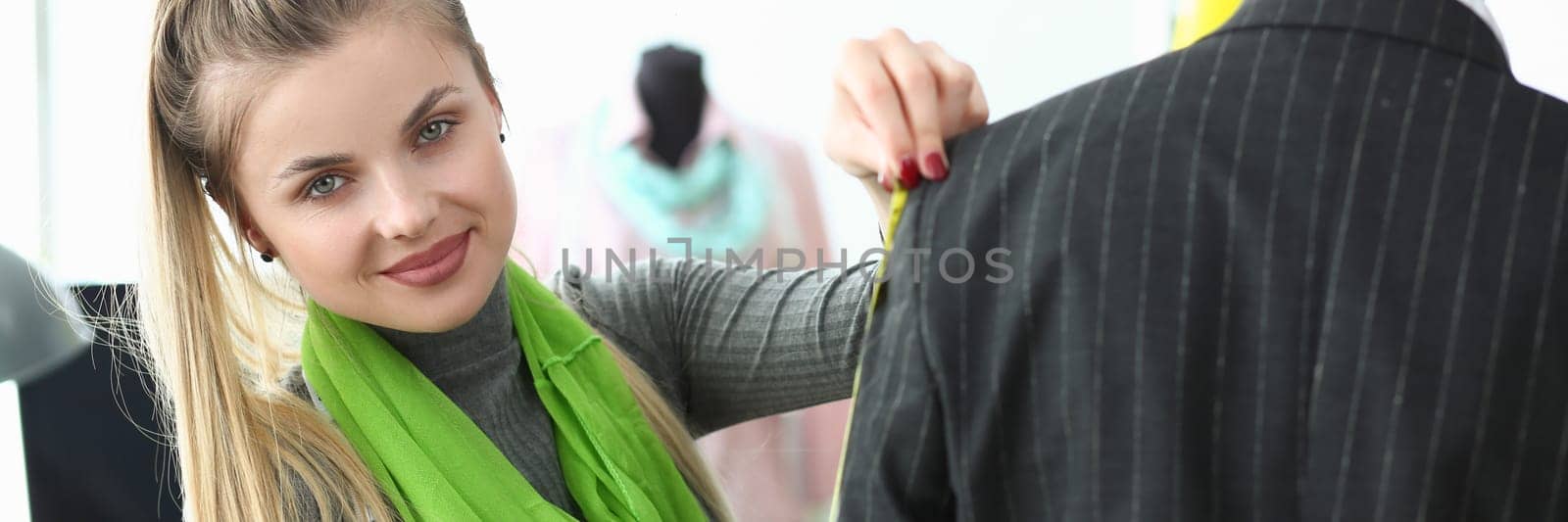 Young beautiful woman seamstress taking suit measurements from modern businessman in atelier by kuprevich