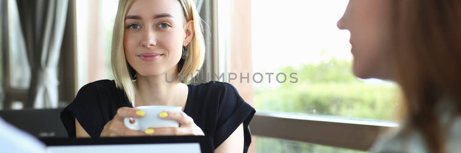 Group of young people at business meeting in cafe. Business people hold tablet at a meeting in cafe and discuss project