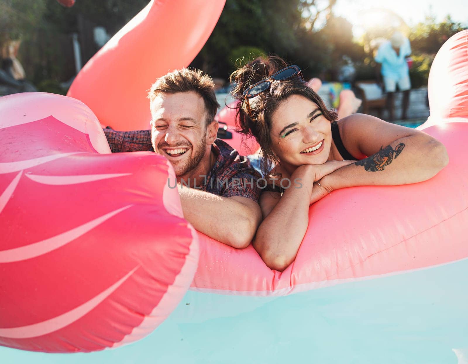Pool party, portrait and happy couple floating in the water together while on vacation at a resort. Float, summer and young man and woman in a swimming pool having fun on a holiday or weekend trip. by YuriArcurs