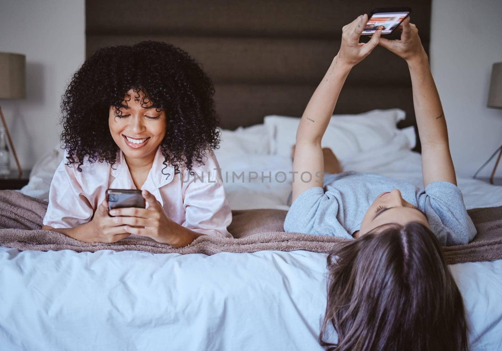 Video call, phone and friends with women at sleepover for communication, internet and contact. Happy, relax and smile with girl lying in bedroom with technology, digital and social media together.