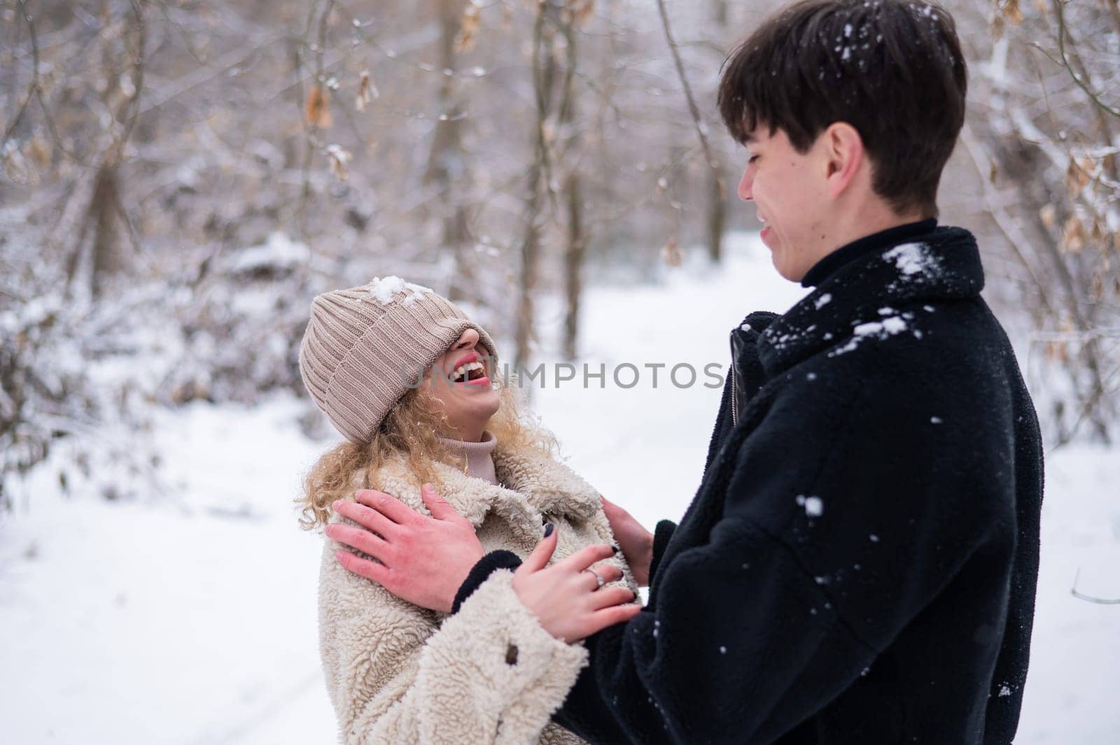 A young couple walks in the park in winter. Guy and girl fooling around on the street