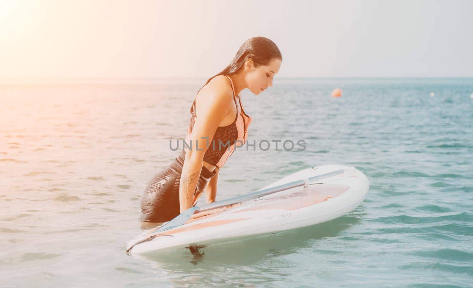 Sea woman sup. Silhouette of happy young woman in pink bikini, surfing on SUP board, confident paddling through water surface. Idyllic sunset. Active lifestyle at sea or river. Slow motion