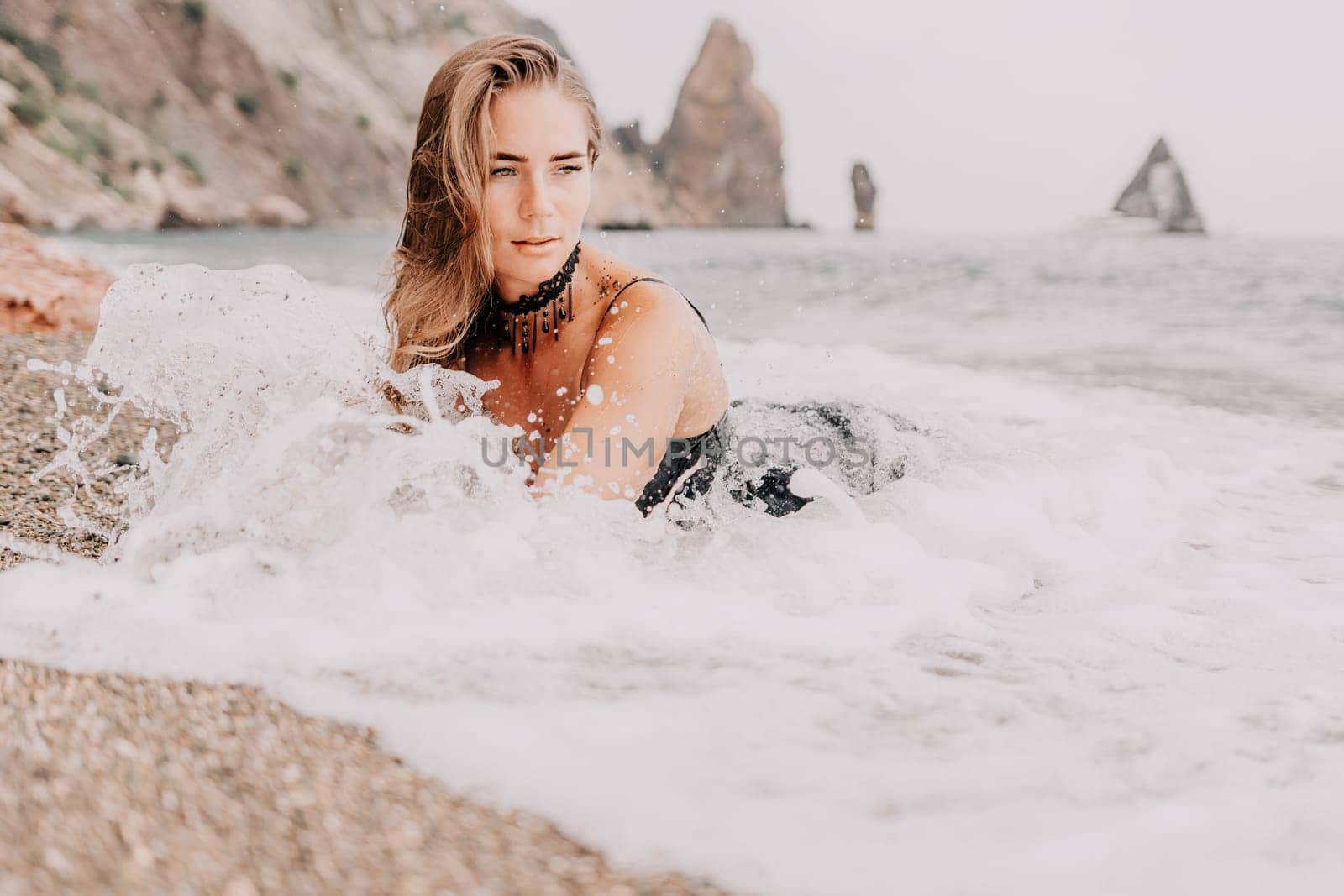 Woman travel sea. Young Happy woman in a long red dress posing on a beach near the sea on background of volcanic rocks, like in Iceland, sharing travel adventure journey