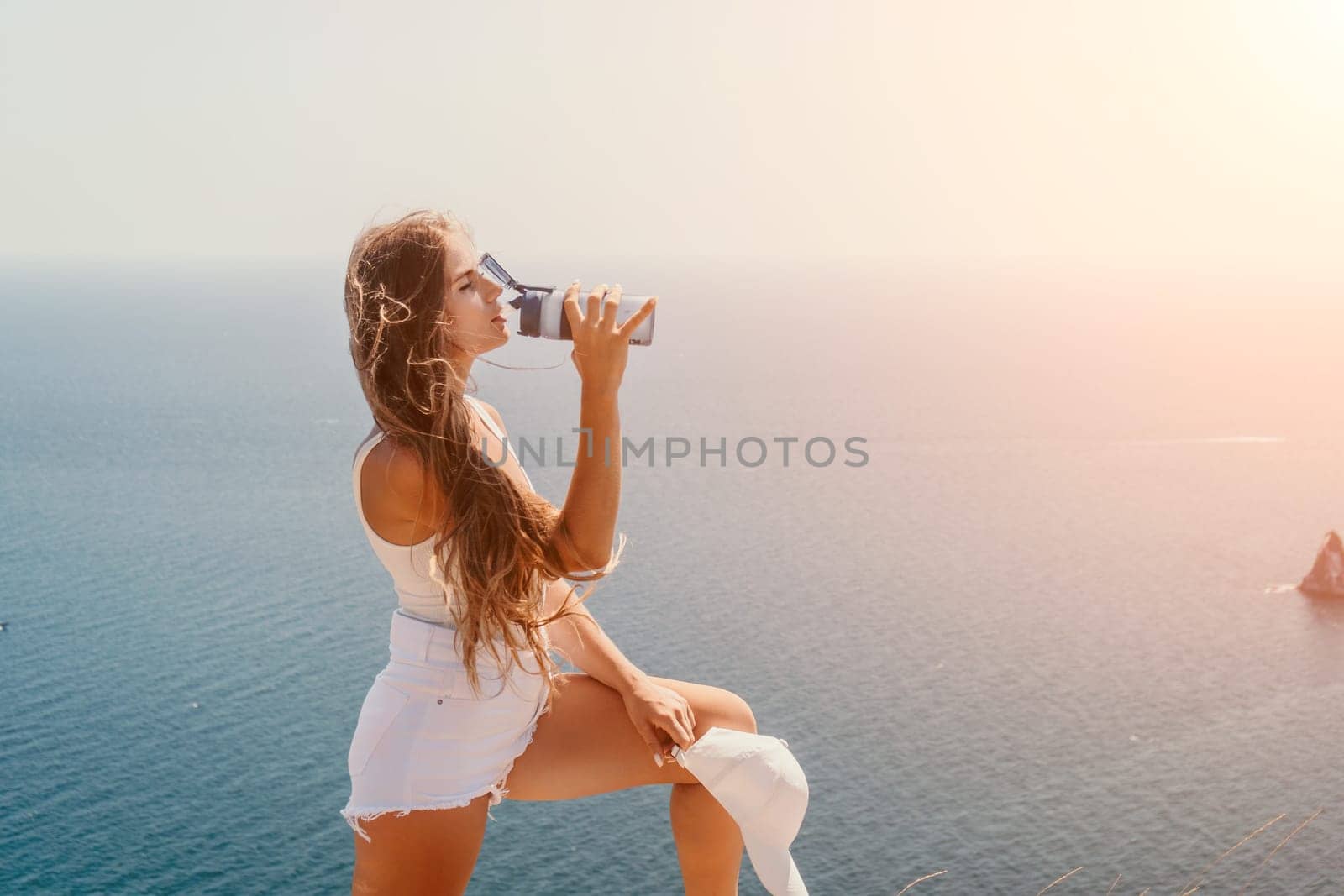 Woman travel sea. Young Happy woman in a long red dress posing on a beach near the sea on background of volcanic rocks, like in Iceland, sharing travel adventure journey