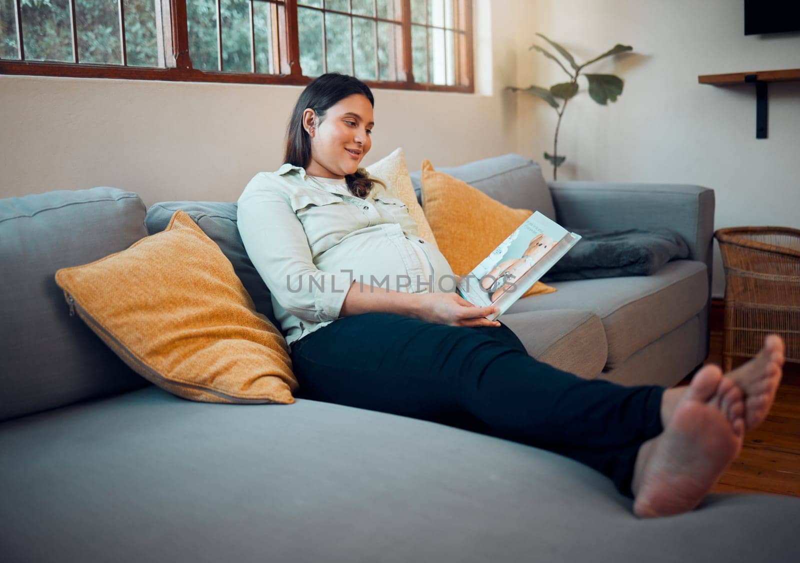 Pregnancy, reading and woman with a book on the sofa for her baby, relax and peace in the living room of a house. Education, calm and happy pregnant mother with a story for her unborn child on couch by YuriArcurs