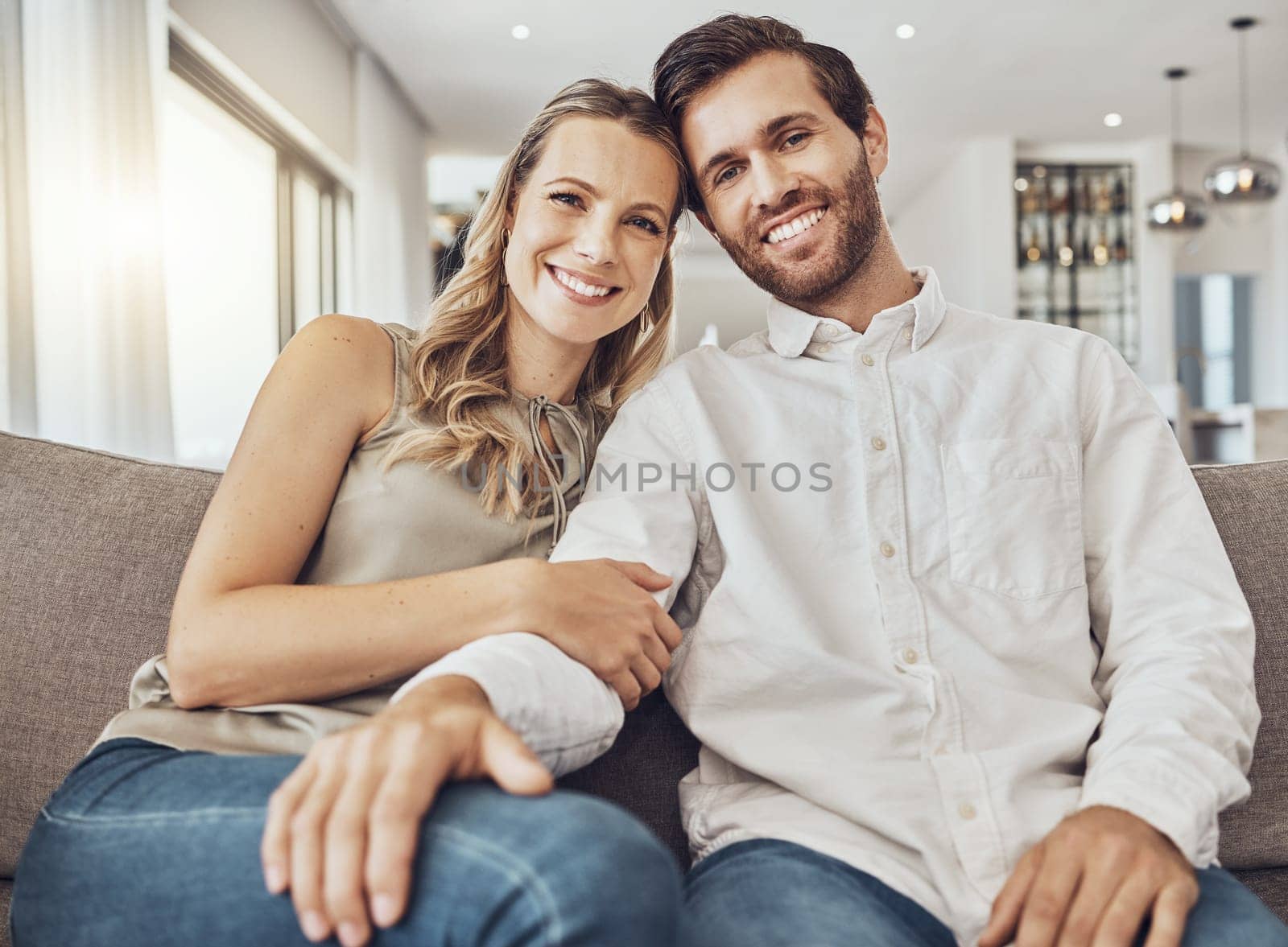 Couple. portrait and home of young people together on a living room couch with love and care. Happiness, smile and hug of a man and woman on a sofa feeling relax in a house lounge with marriage by YuriArcurs