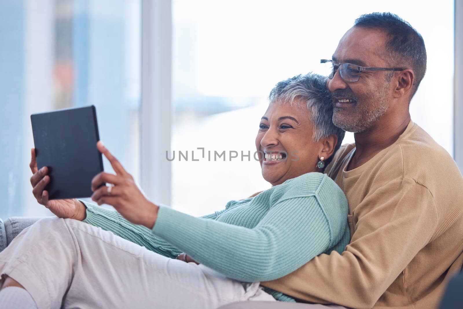 Movie, communication and senior couple with a tablet, streaming film and show on the living room sofa of their house. Website, social media and elderly man and woman with comedy and app on tech.