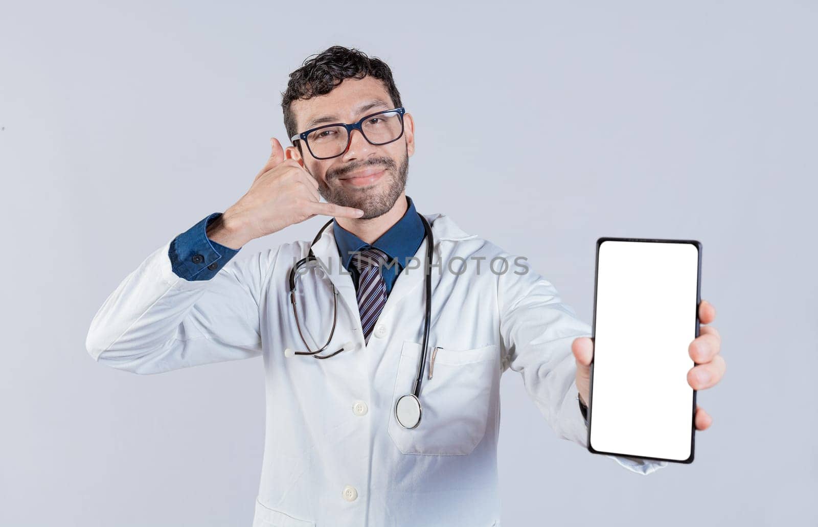 Handsome doctor showing cellphone screen gesturing call me. Happy doctor showing white screen of cellphone