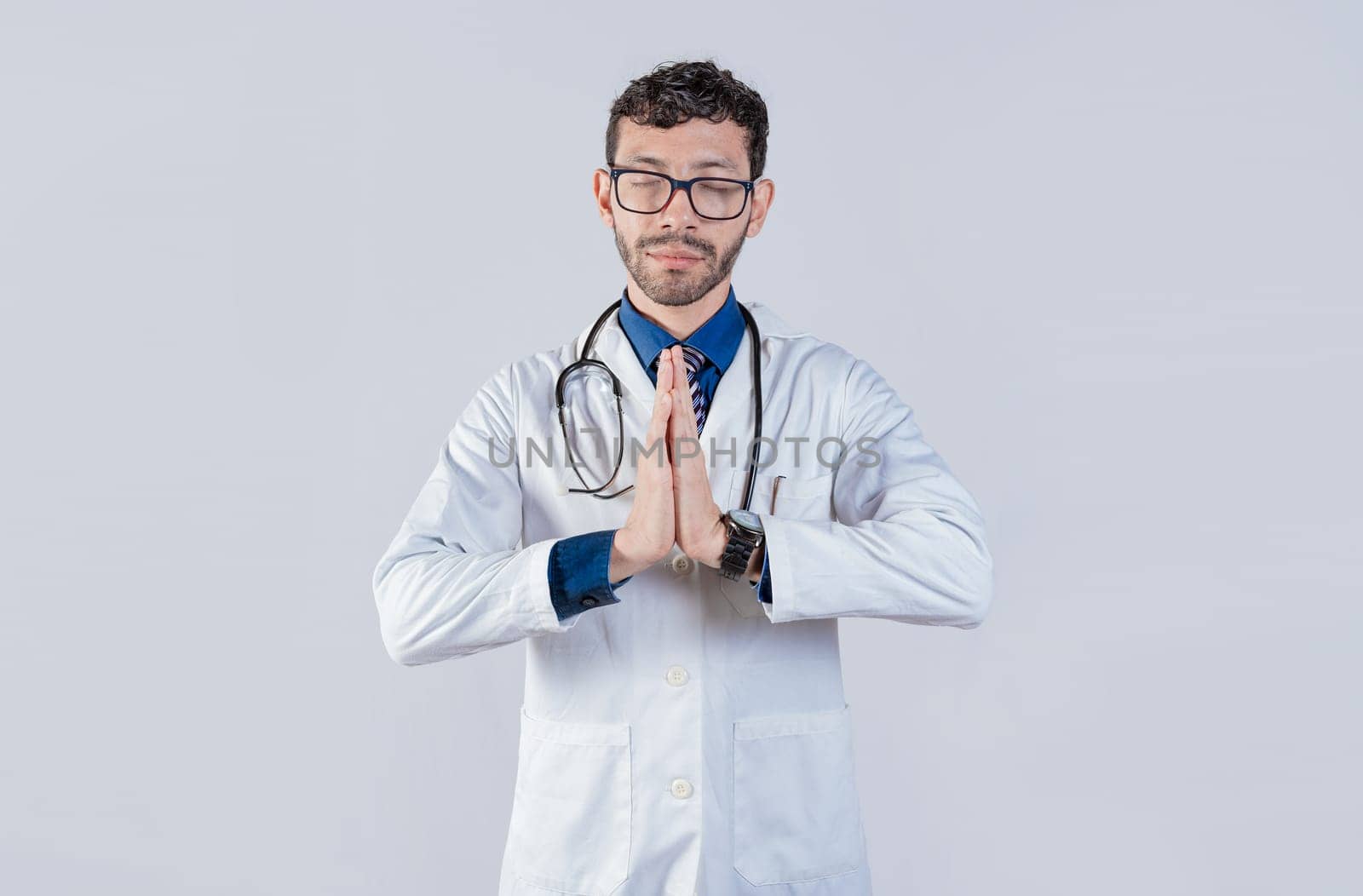 Doctor praying with hands together on isolated background. Young doctor praying with hands together isolated
