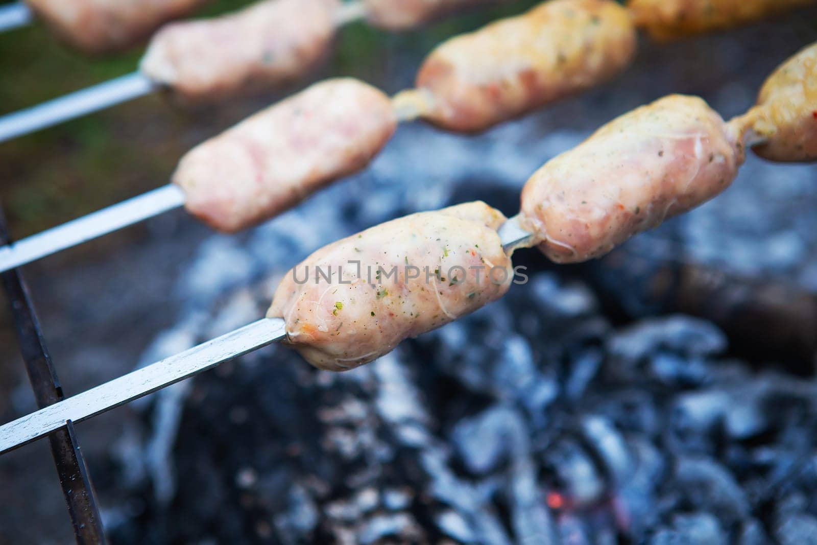 Delicious sausages on a skewer. Rest, friends outdoors