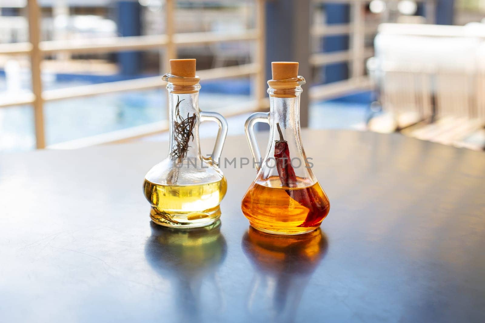 On the table are two glass bottles filled with spicy and rosemary olive oil. Close-up. Butter for pizza, rest in an Italian restaurant
