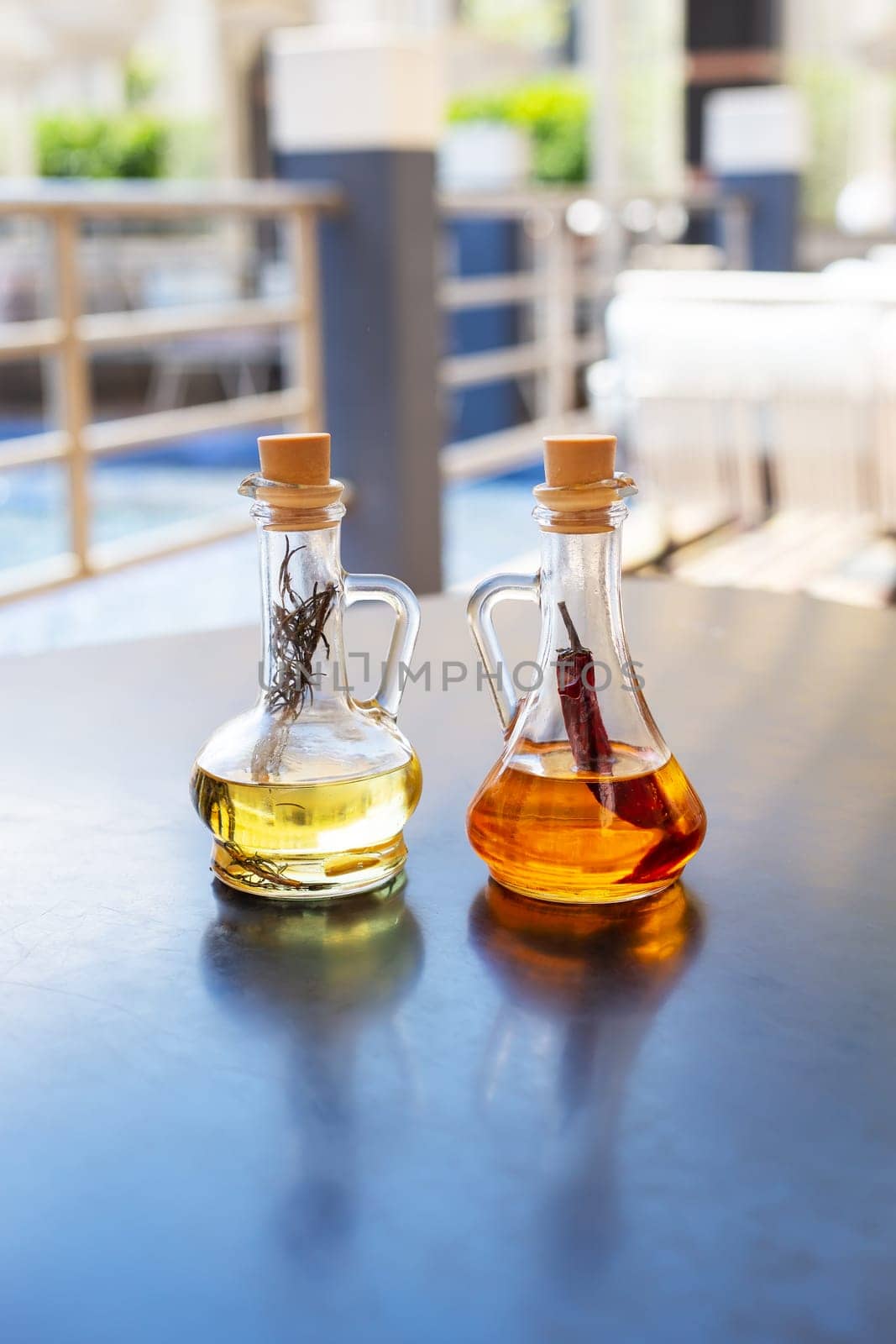 On the table are two glass bottles filled with spicy and rosemary olive oil. Close-up. Butter for pizza, rest in an Italian restaurant