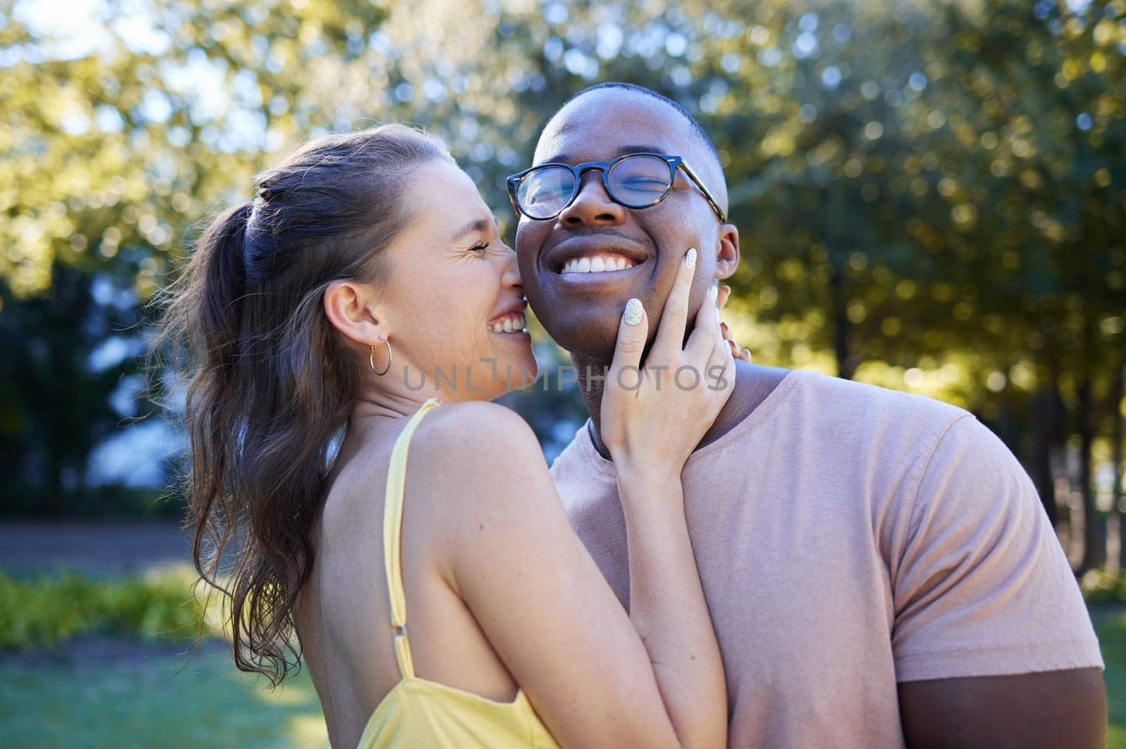 Summer, love and laugh with an interracial couple bonding outdoor together in a park or garden. Nature, diversity and romance with a man and woman hugging while on a date outside in the countryside by YuriArcurs