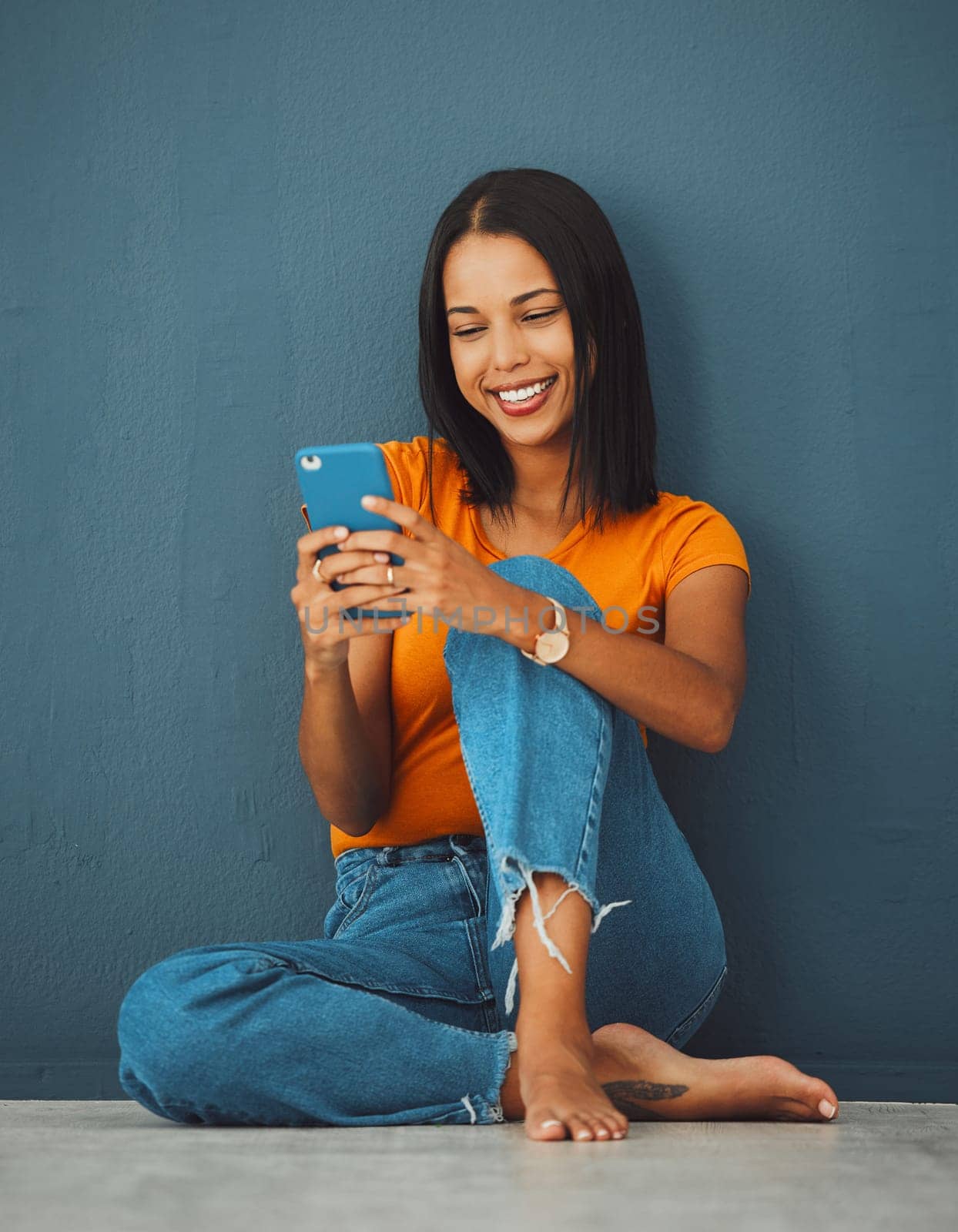 Happiness, black woman on floor and smartphone for connection, smile and communication on dark studio background. Female, lady and cellphone for typing, texting and social media for online reading by YuriArcurs