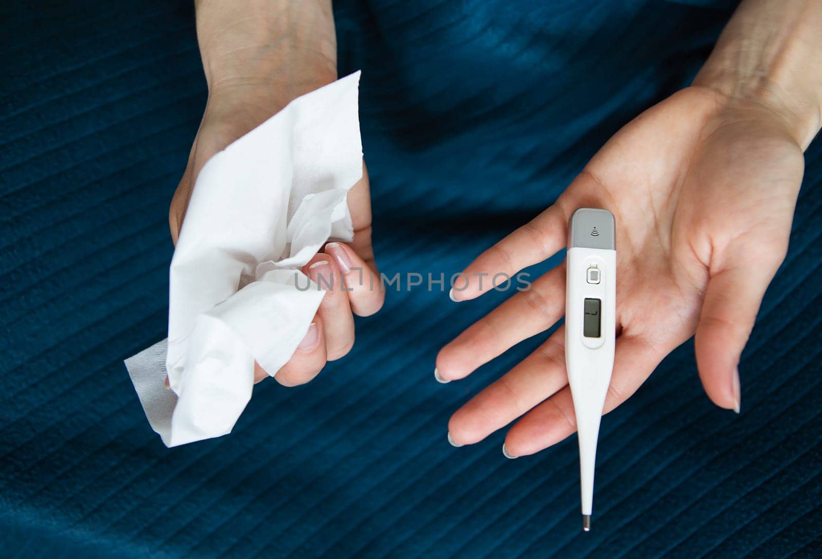 The girl holds a paper towel in her right hand and a thermometer in her left. Arms extended in front of you. The concept of self-control and self-control in viruses and epidemics.