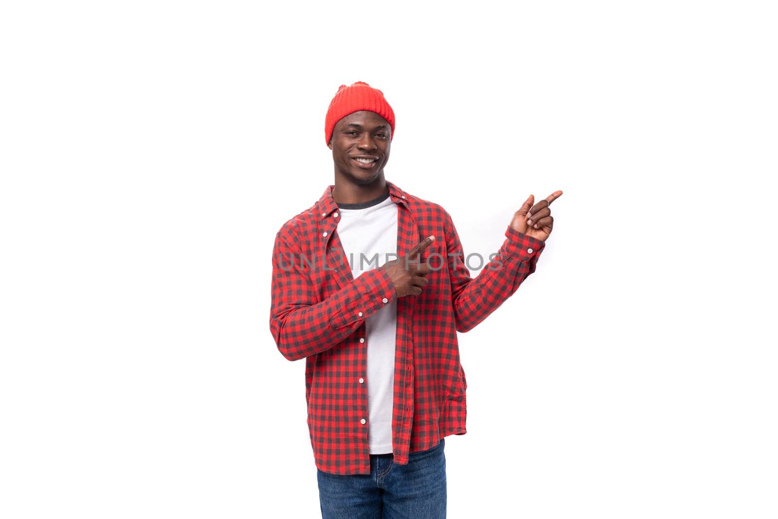 portrait of handsome 30s black american man dressed in red shirt and cap telling news with finger on white studio background with copy space by TRMK