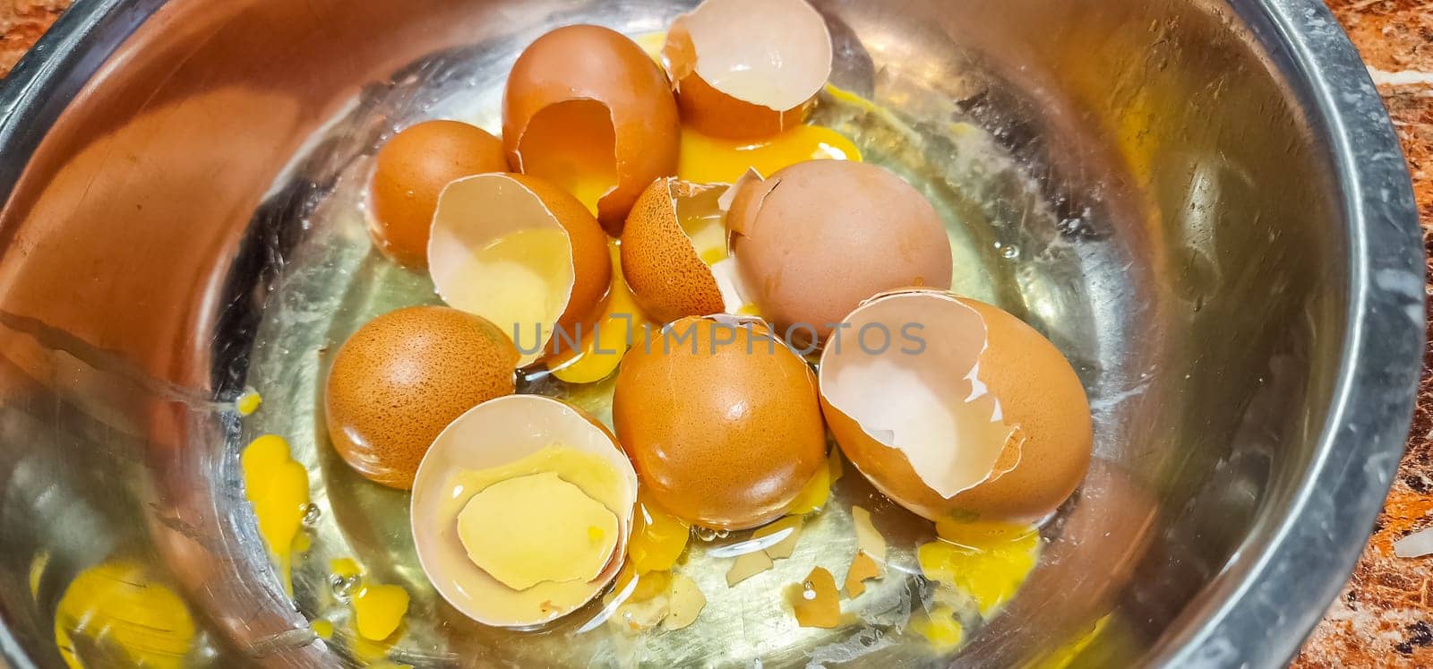 Overhead view of broken eggs in bowl by shells on table