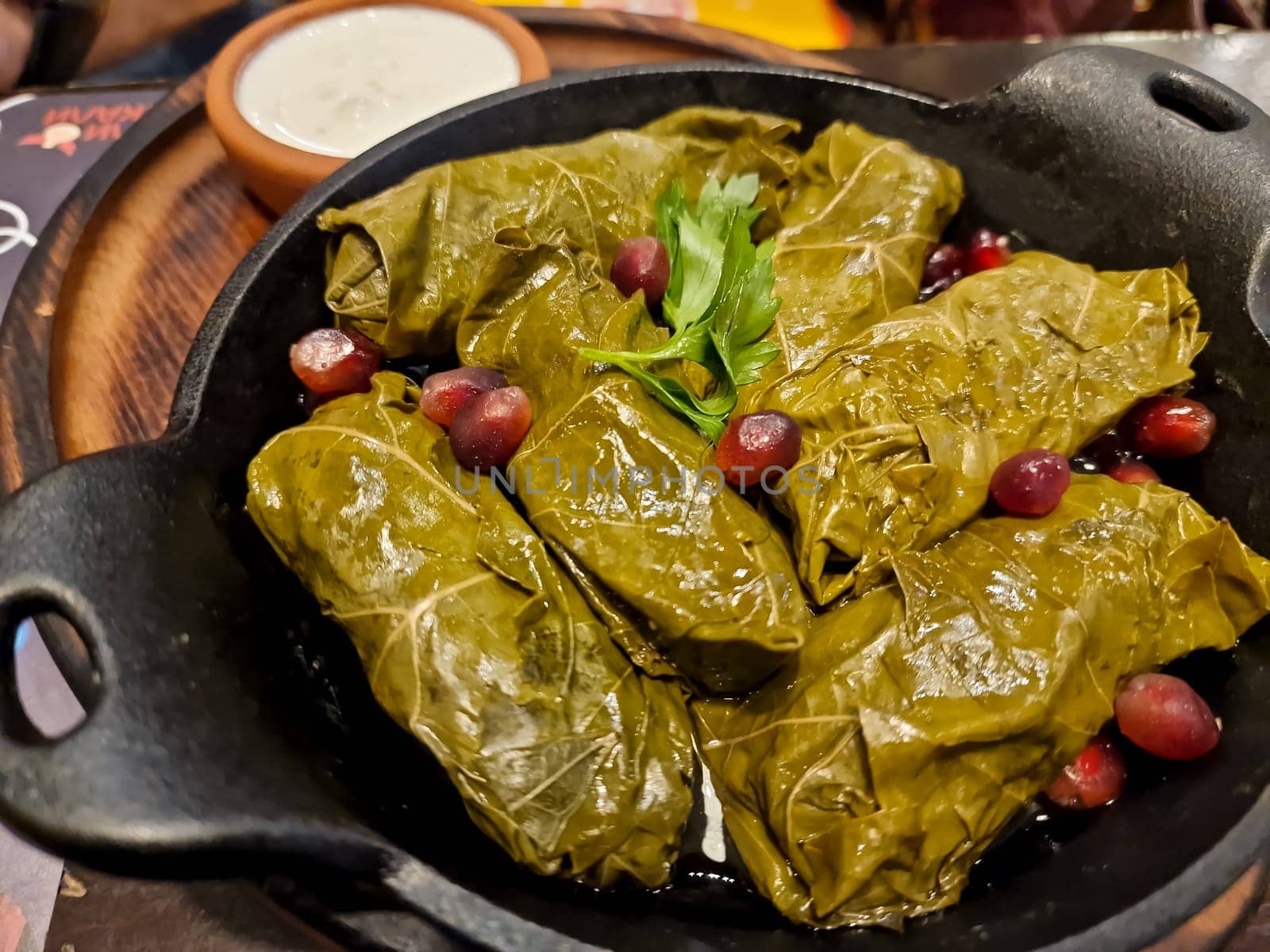 Delicious stuffed grape leaves ,traditional doom Mediterranean cuisine Dolma, on a black plate with fresh cilantro and dill on dark wooden background top view with copyspace