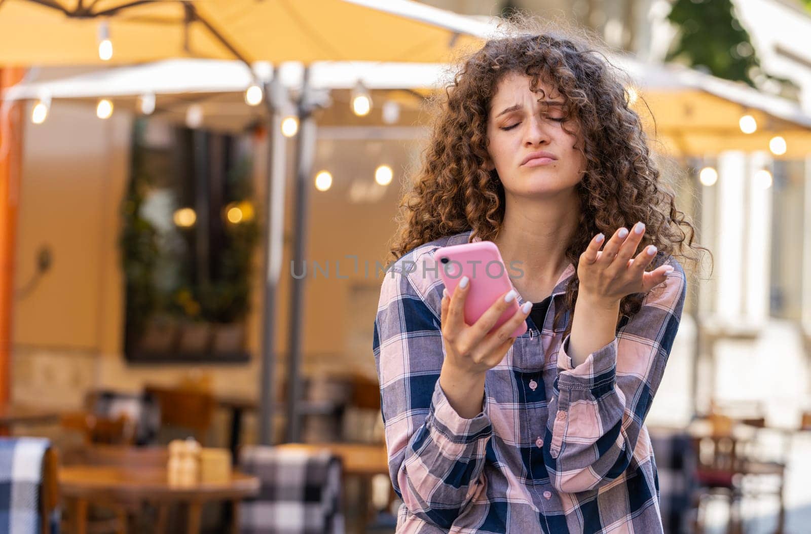 Pretty young woman use smartphone typing browsing, loses becoming surprised sudden lottery results, bad news, fortune loss, fail. Girl walking in urban sunshine city street outdoors. Town lifestyles