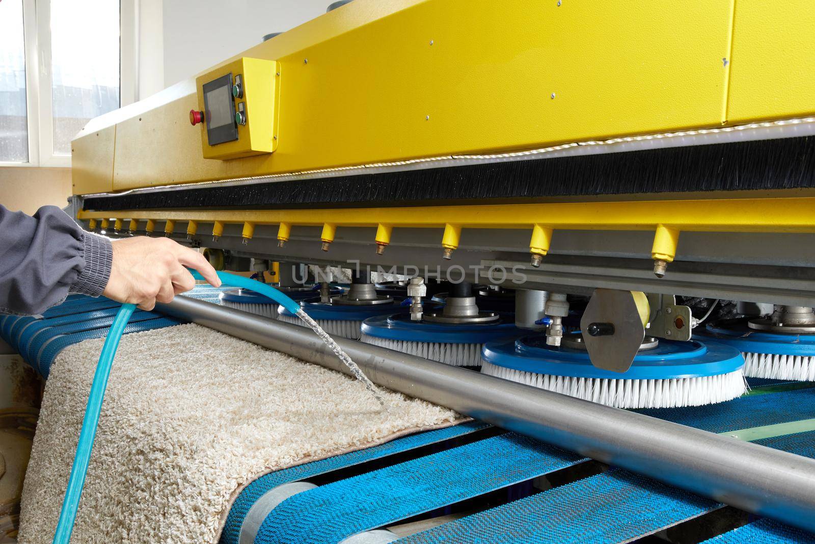 Man worker cleaning carpet on automatic washing machine equipment and dryer in the Laundry room