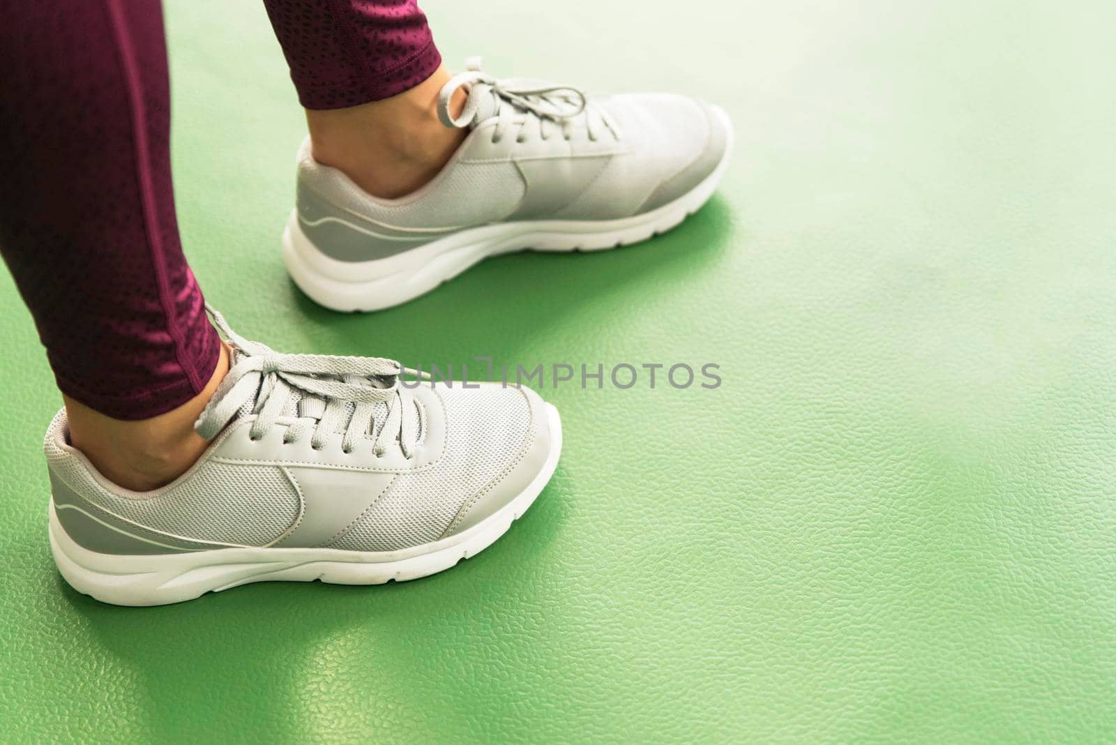Close up front view of woman's hands tying shoelaces on sneakers in the gym.