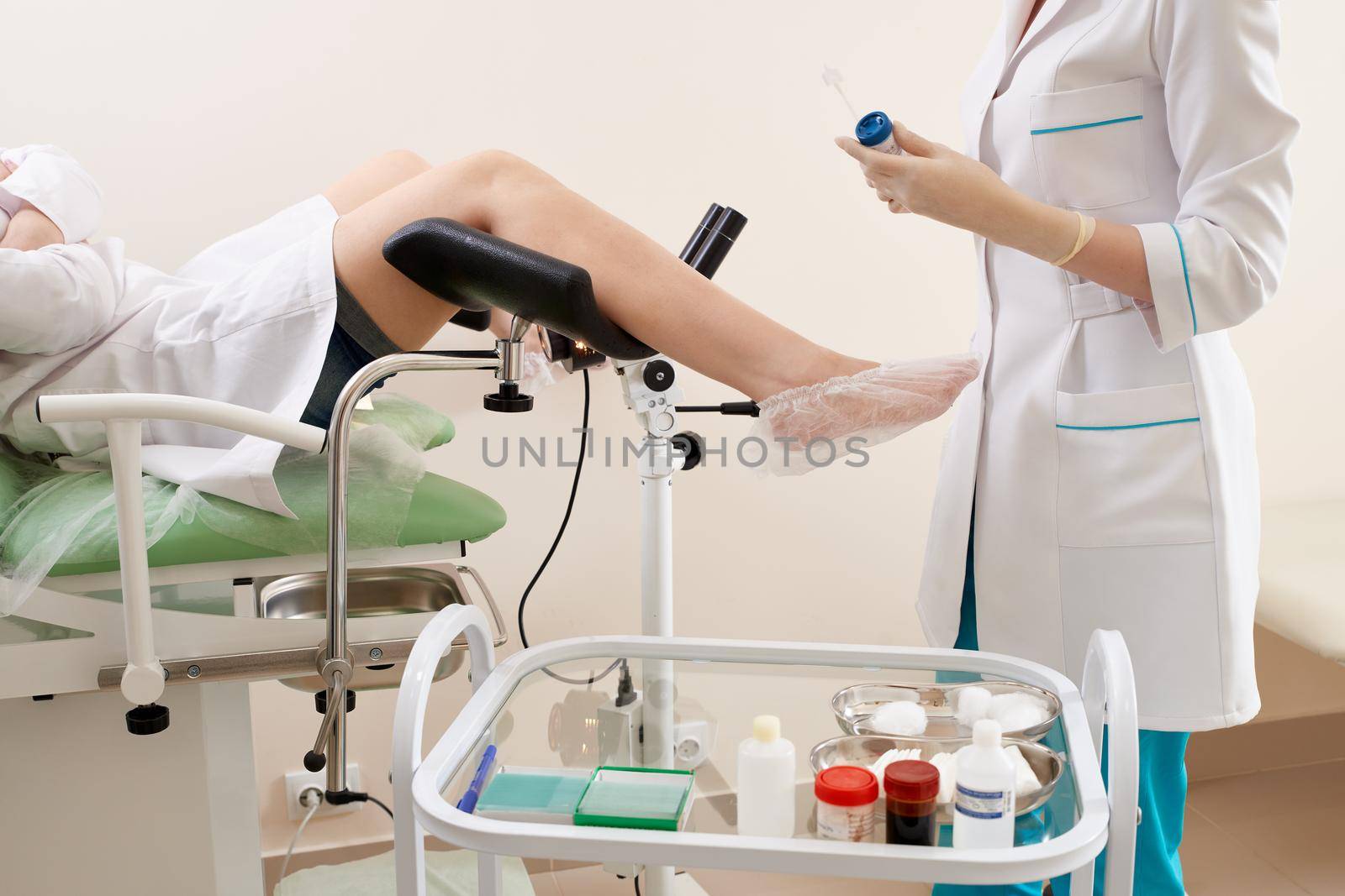 Gynecologist preparing for an examination procedure for a woman sitting on a gynecological chair