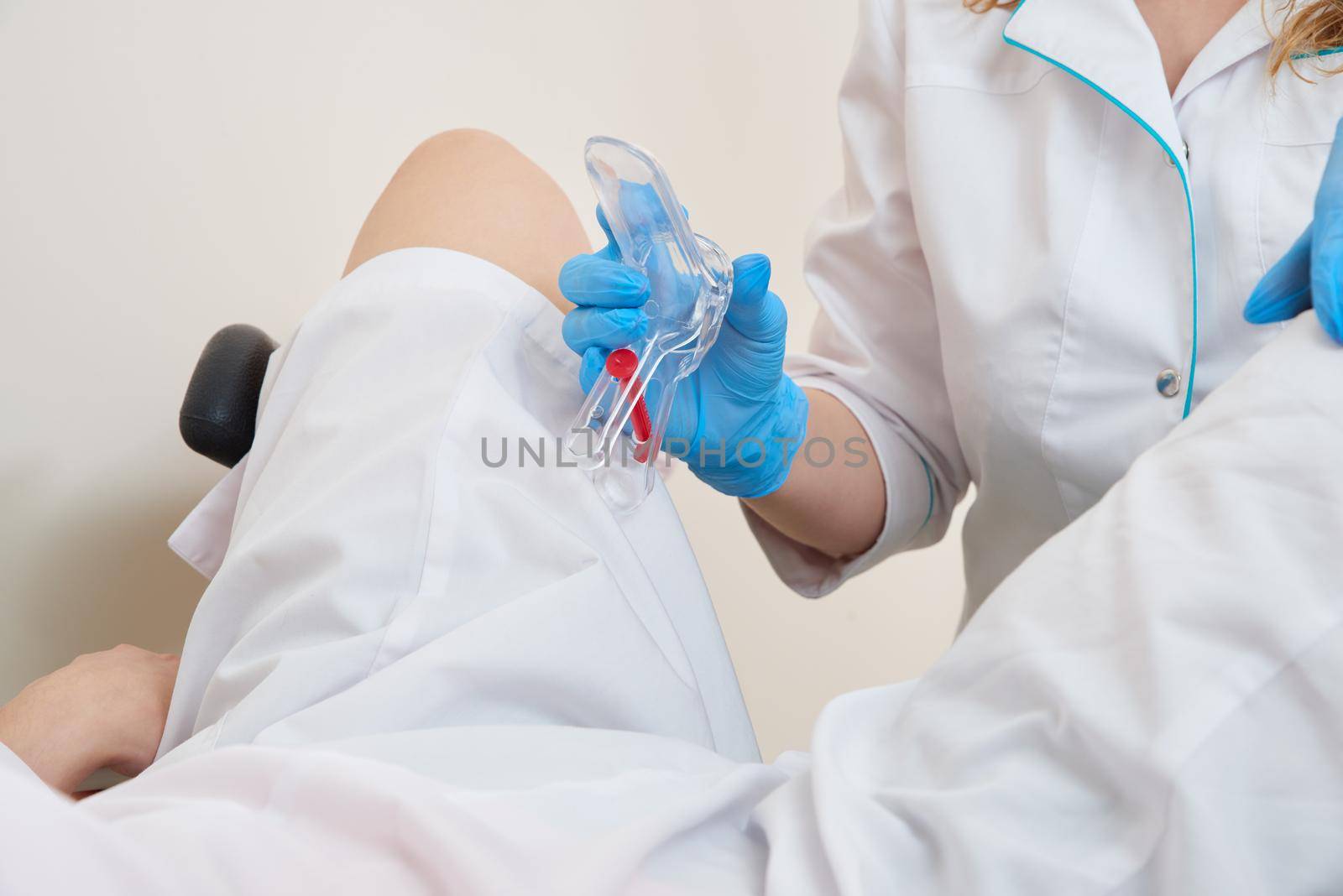 gynecologist holds a mirror for vaginal examination of the patient