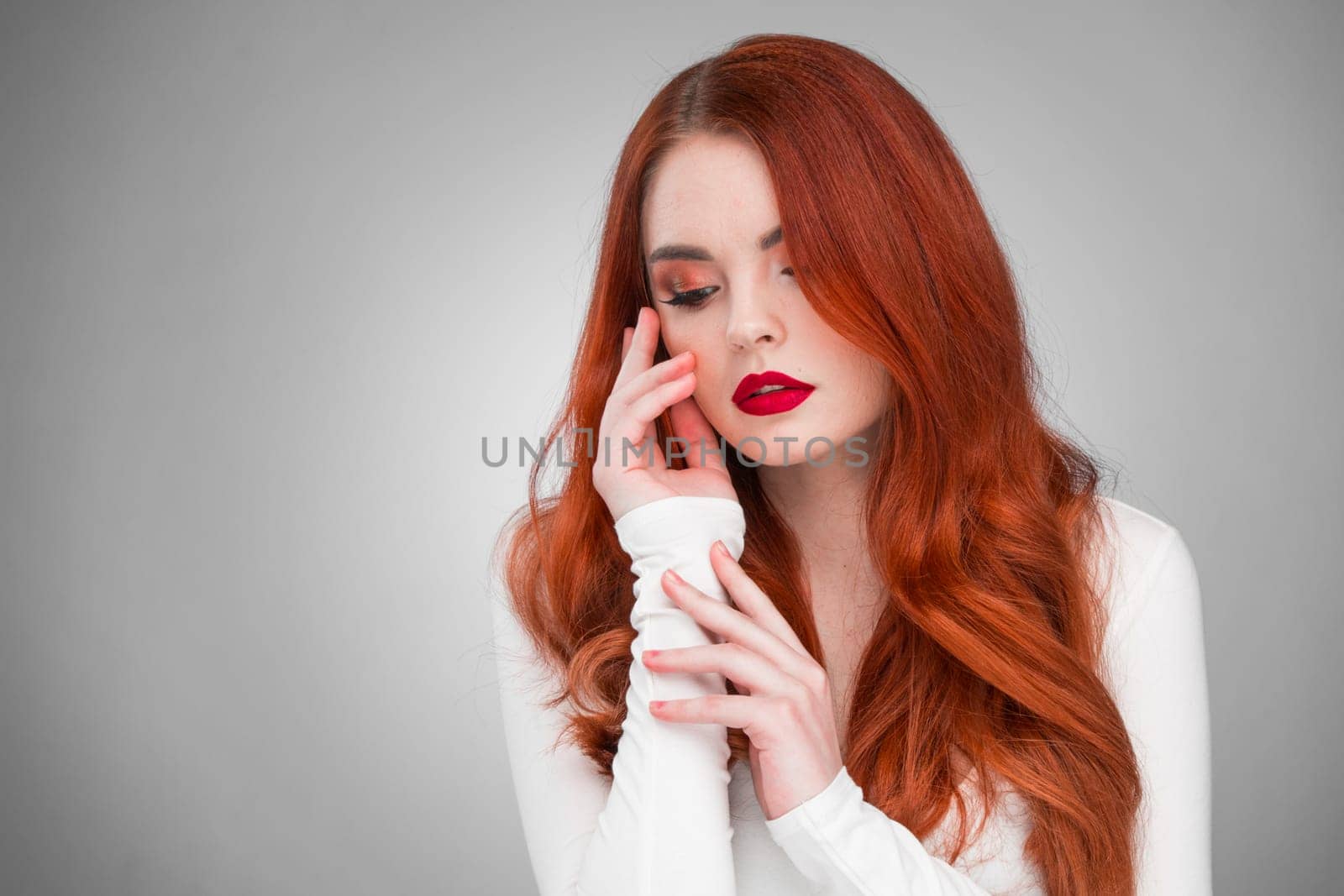 Gorgeous redhead girl with wavy hair beauty studio portrait