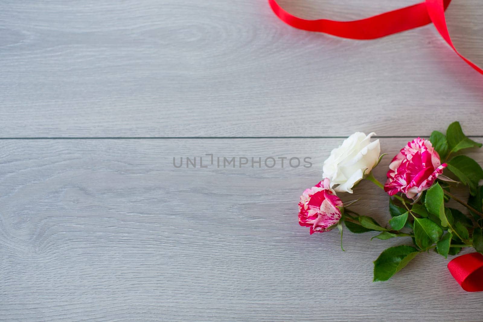 Floral background of pink, red and other roses on a light wooden table