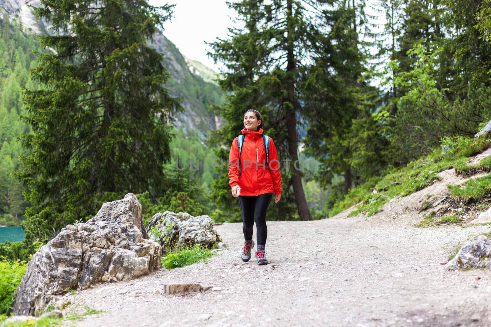 Spiritually strong woman hiking alone in the mountains in red raincoat.