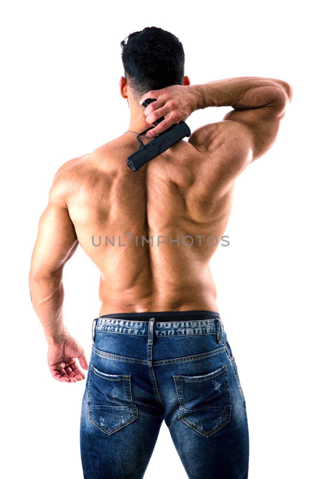 Handsome man with naked muscular torso holding hand gun, on white background, seen from the back