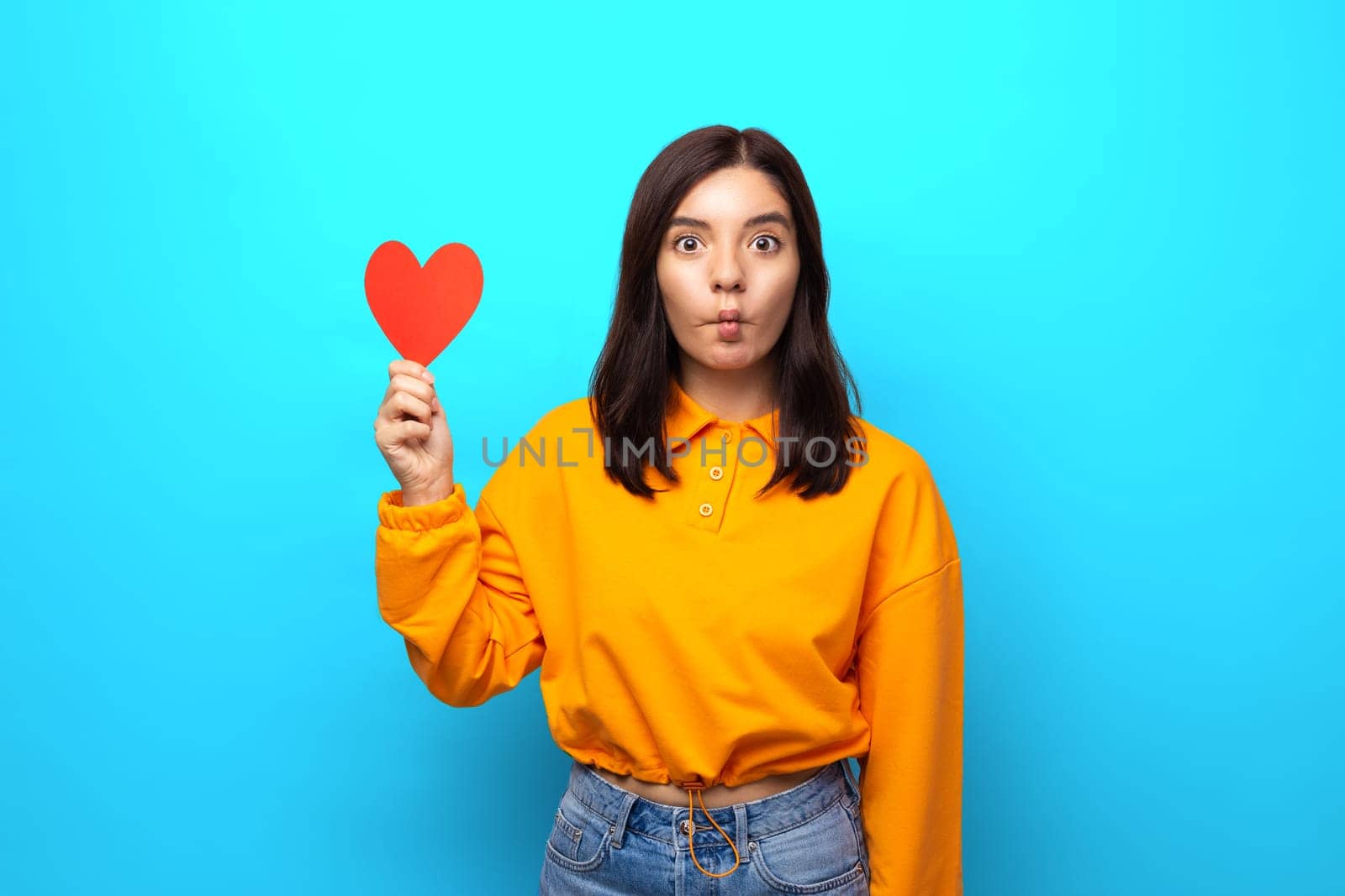 amazing mixed races woman with funny face holding up big heart-shaped valentine.