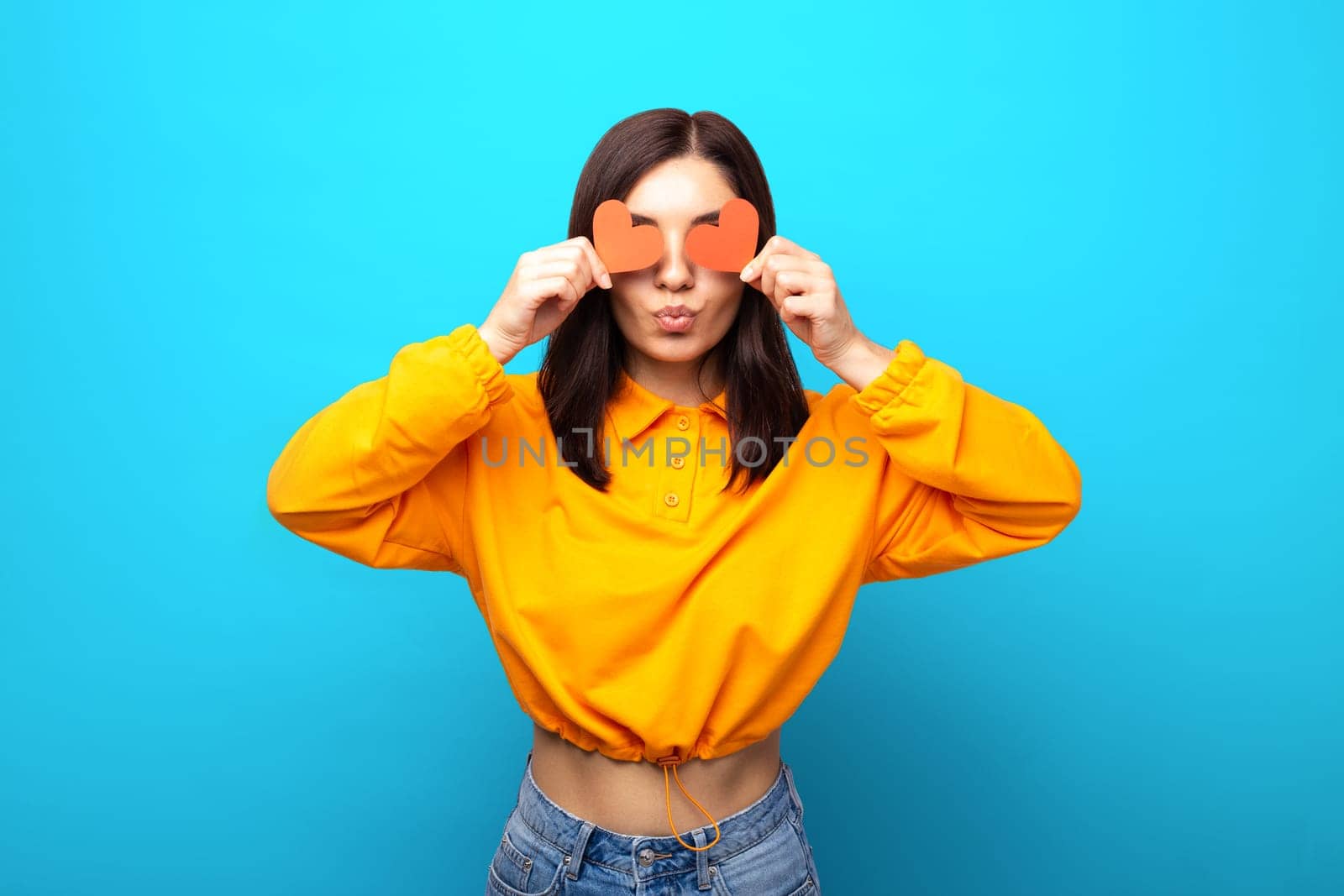 amazing looking mixed races woman with funny face covering her eyes with valentines red hearts giving a kiss.