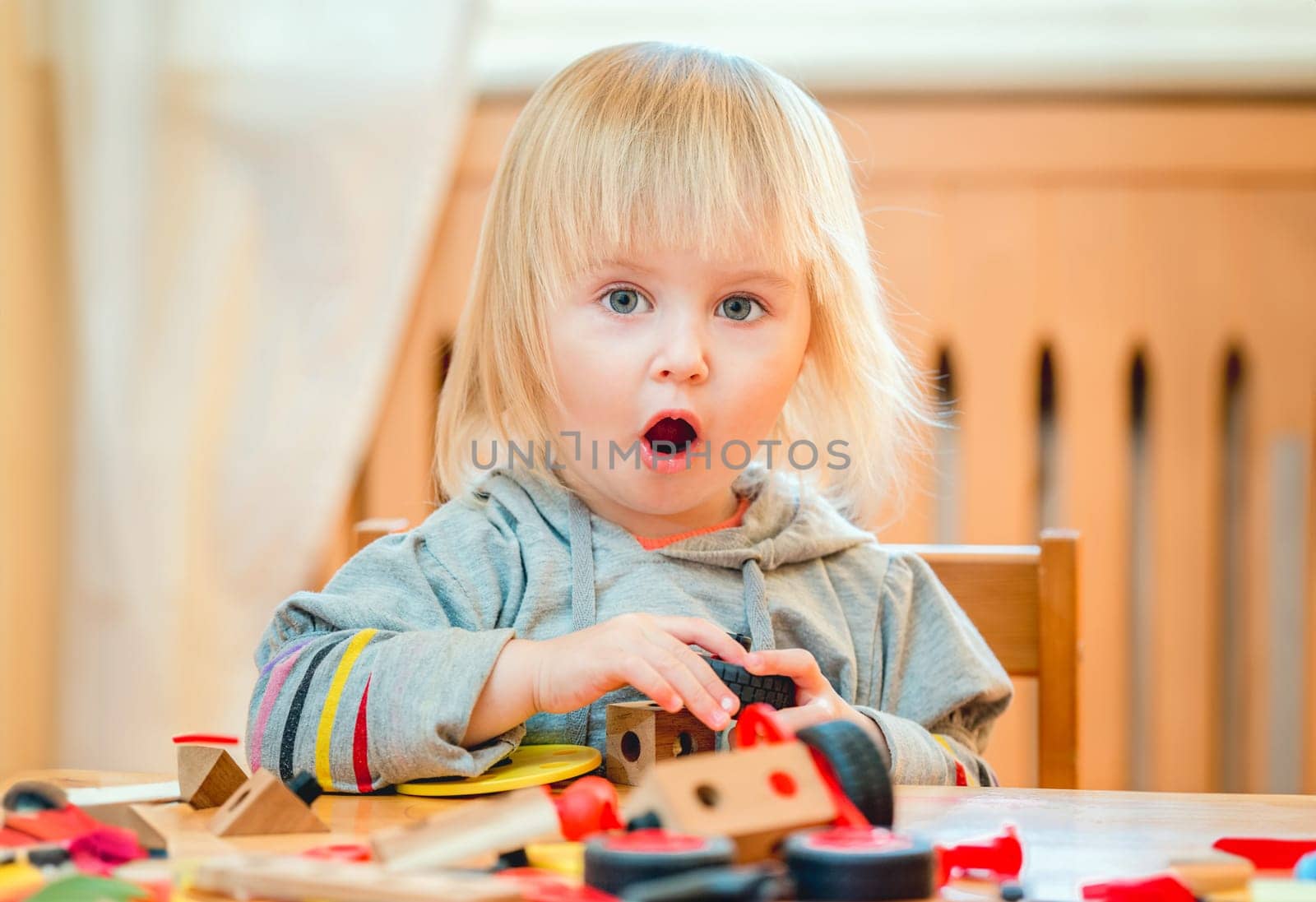 cute two-year old baby girl at home in the nursery playing with constructor