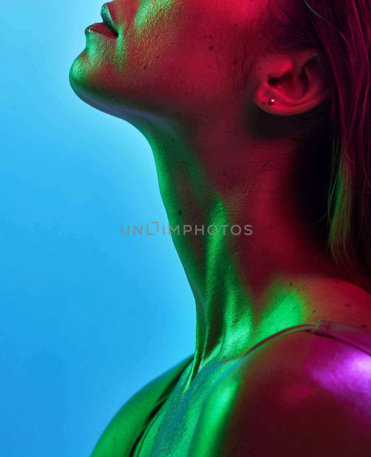 Woman neck, skincare or neon lighting on isolated blue background in trendy, cool or stylish fantasy art in studio. Zoom, beauty or model body glow in creative aesthetic, green or pink lights texture by YuriArcurs