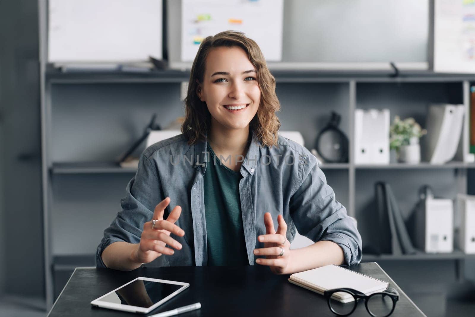 A sophisticated businesswoman is engaging in a video conference from her office or home. She's attentively looking into the web camera, articulating her thoughts and ideas with clarity and confidence