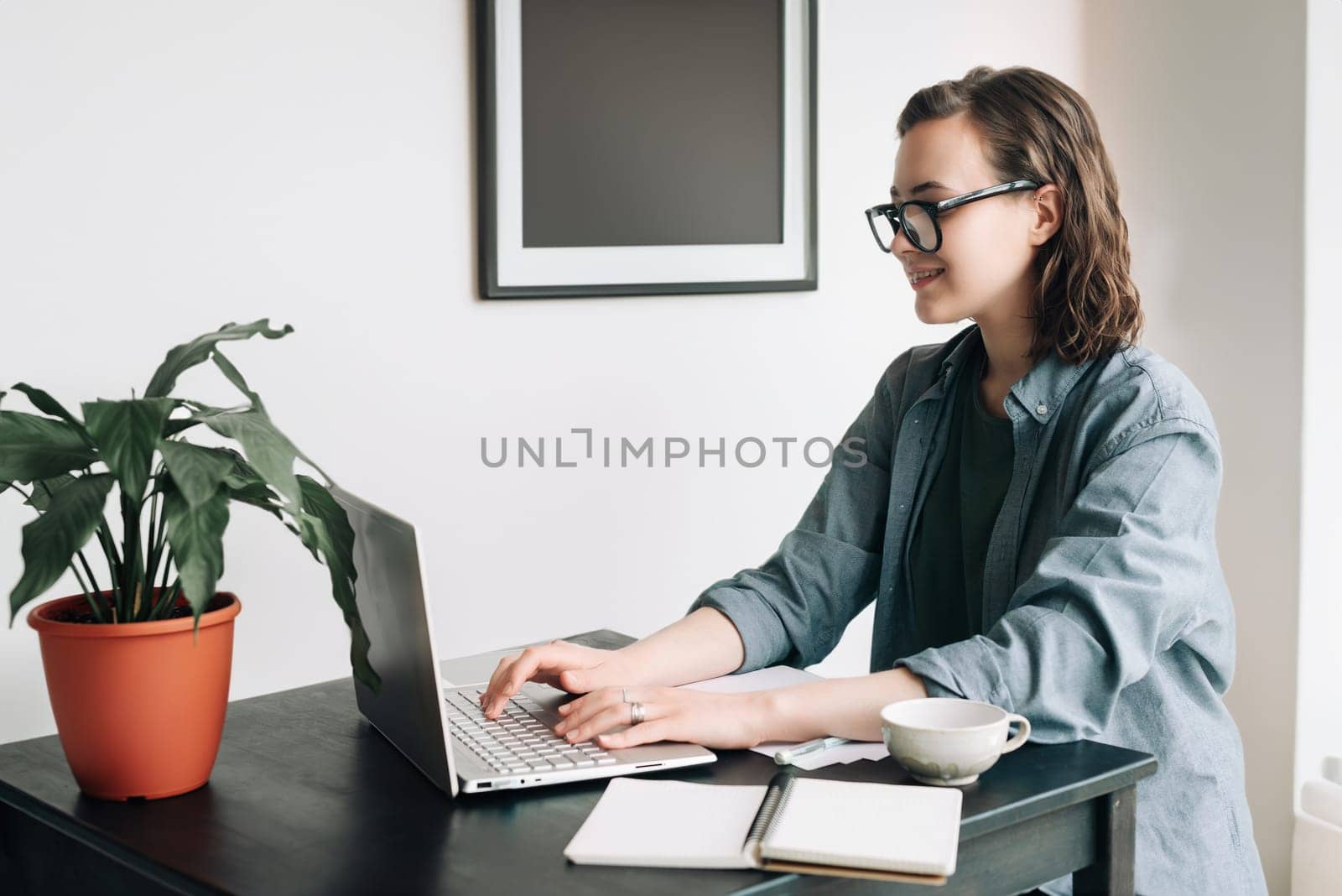 Professional young woman using laptop in office. Student girl working remotely from home. Work or study from home, freelance, business, and lifestyle concept. Technology, productivity, education.