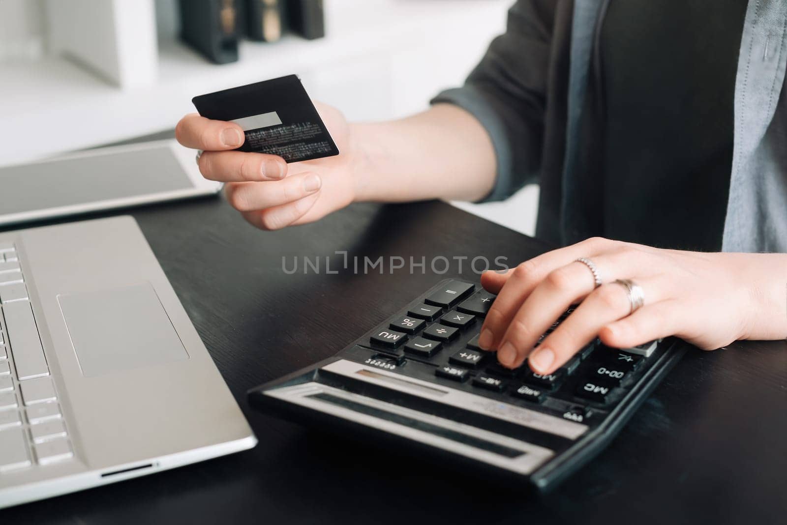 Woman accountant in office, using calculator and holding credit card. Close-up of hands. Online shopping and finance concept. Financial management, digital transactions, business and finance.