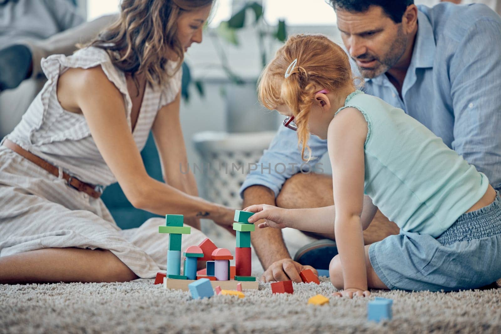 Family, building blocks and girl playing or learning in home, having fun and bonding with parents. Development, love and support of caring father and mother with kid enjoying toys together in house