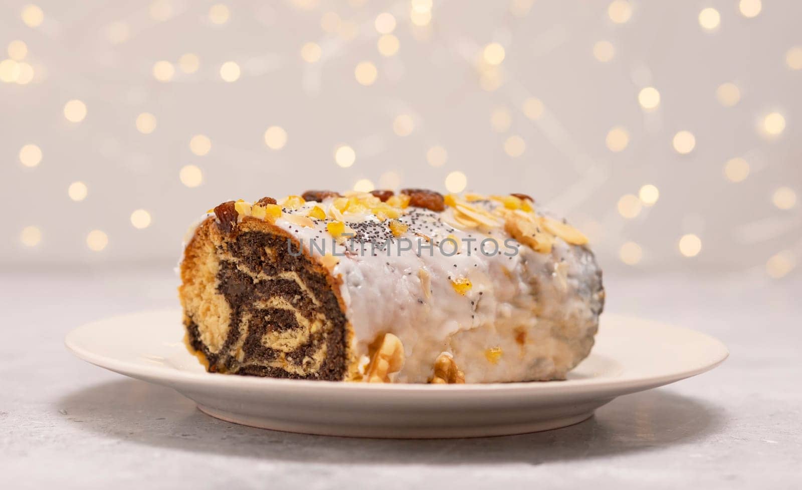 Christmas Polish strudel Makowiec with poppy seeds, traditional polish festive cake covered with sugar icing, walnuts, dried fruits on white background with lightening. Horizontal plane.Winter holiday.