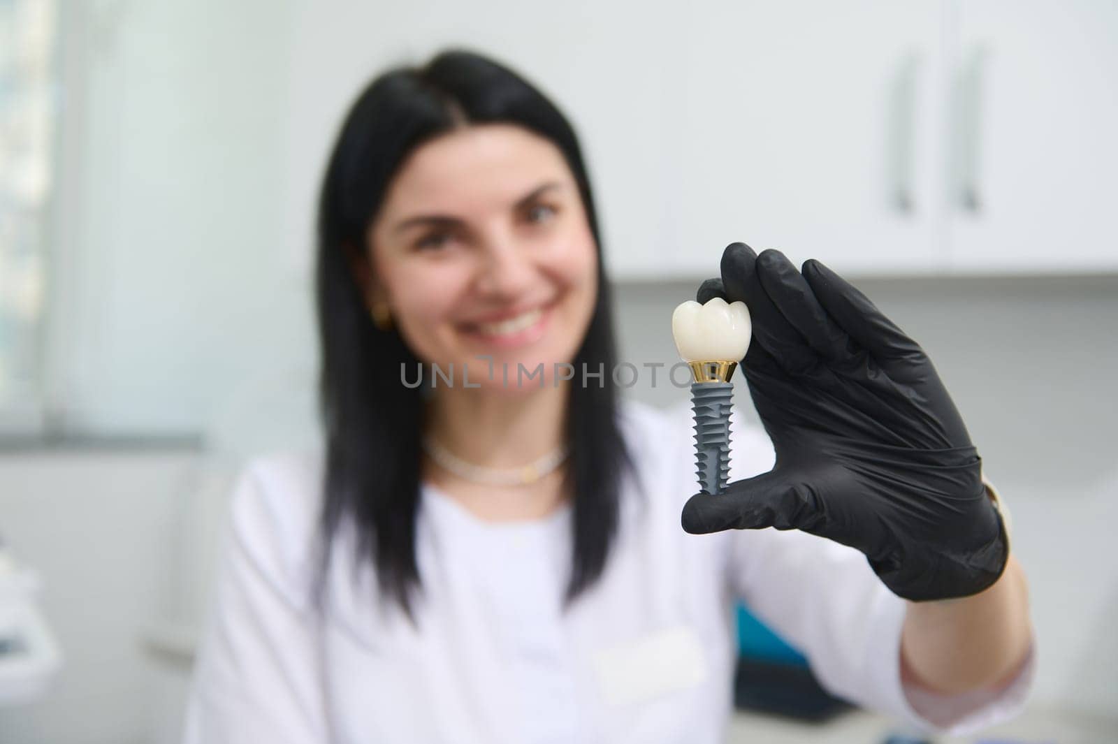 Denture. Dental implant. Maxillofacial Surgery. Close-up dentist's hand holds a model of a tooth showing the mechanism of implant installation. Dental prosthesis. Orthodontics. Cosmetic dentistry