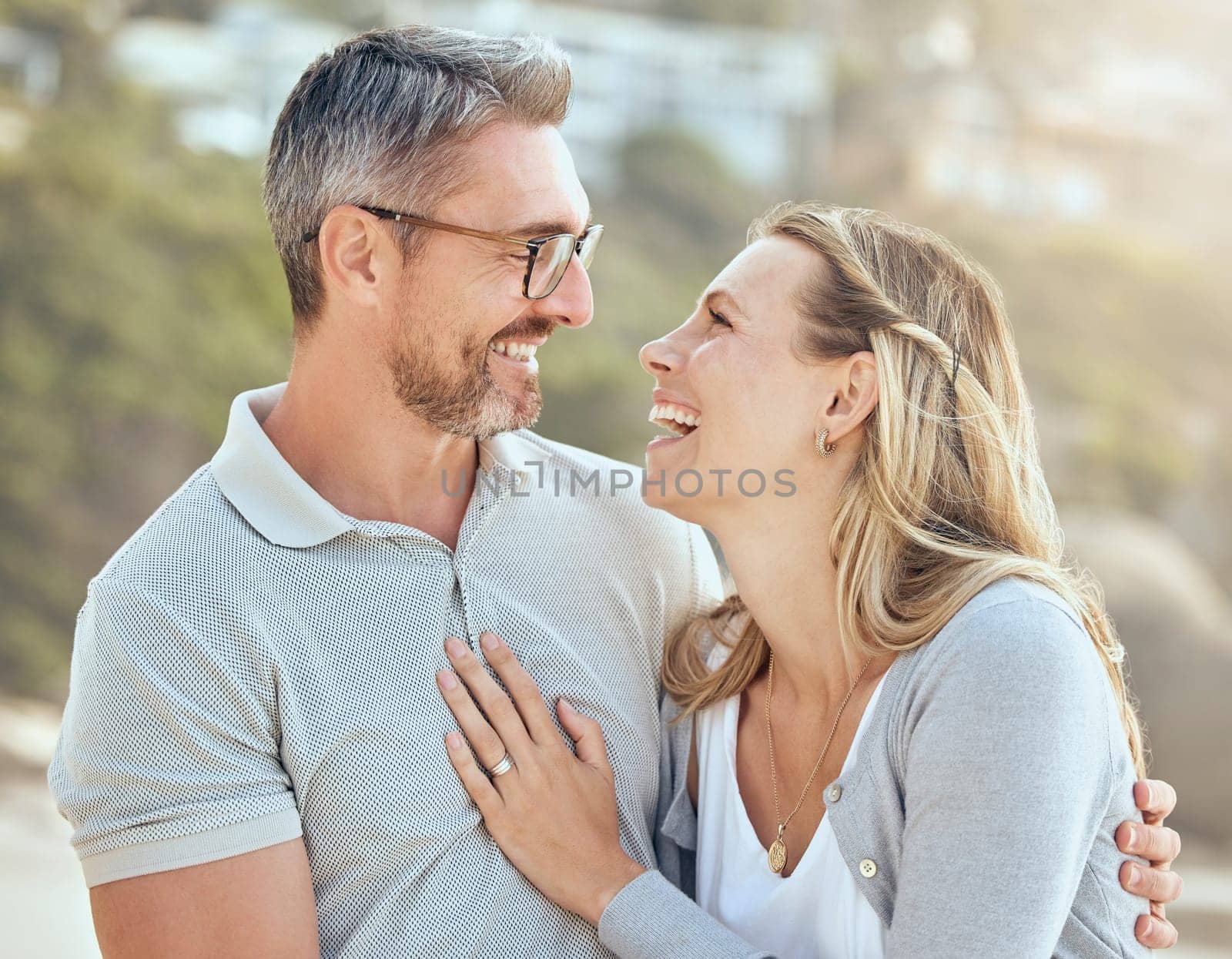 Happy, smile and love with couple at beach for laughing, travel and summer vacation. Happiness, holiday and romance with man and woman hugging on seaside date for bonding, affectionate and care.