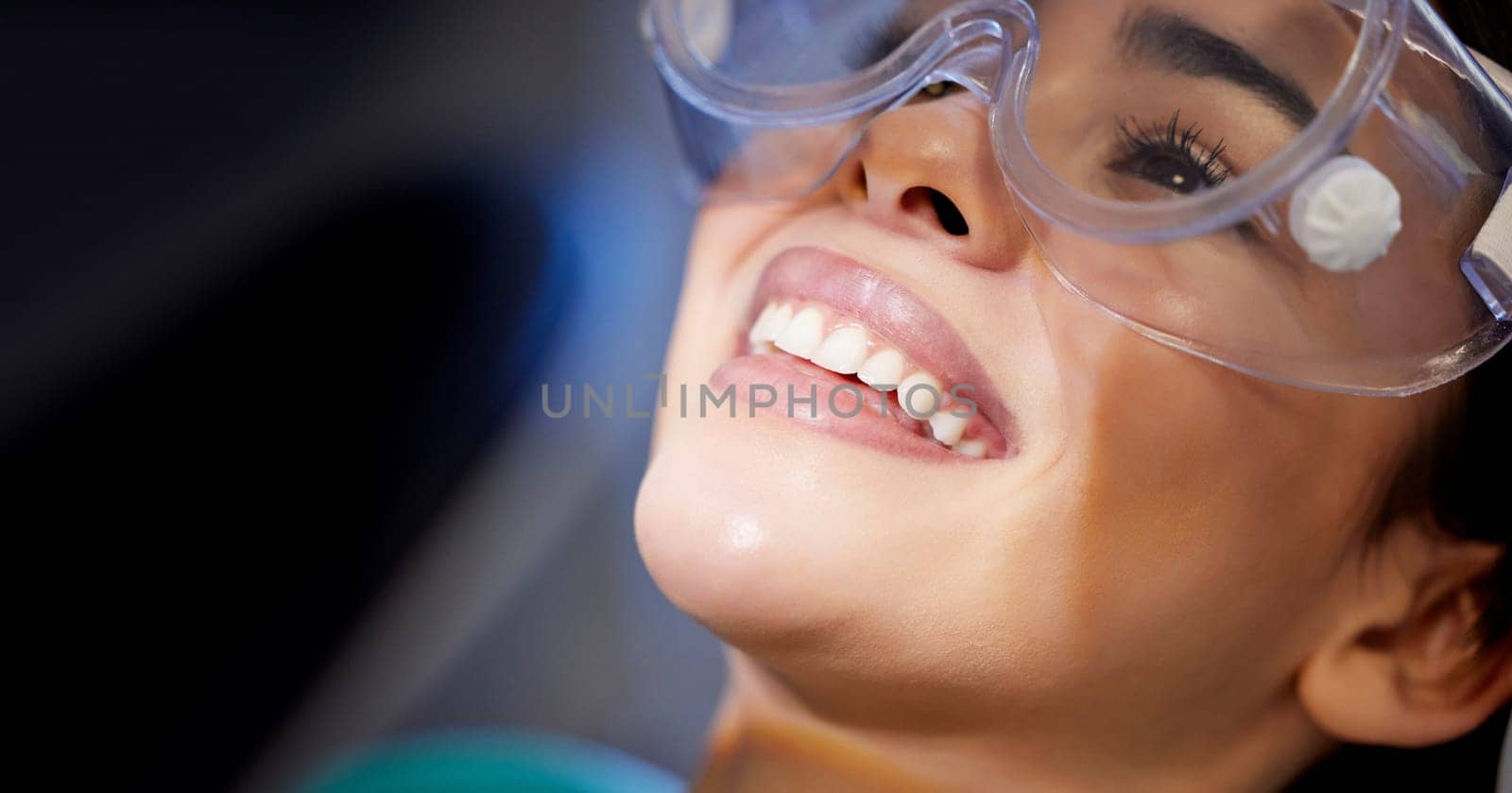 Feels good to smile again. a young woman wearing goggles during a dental procedure