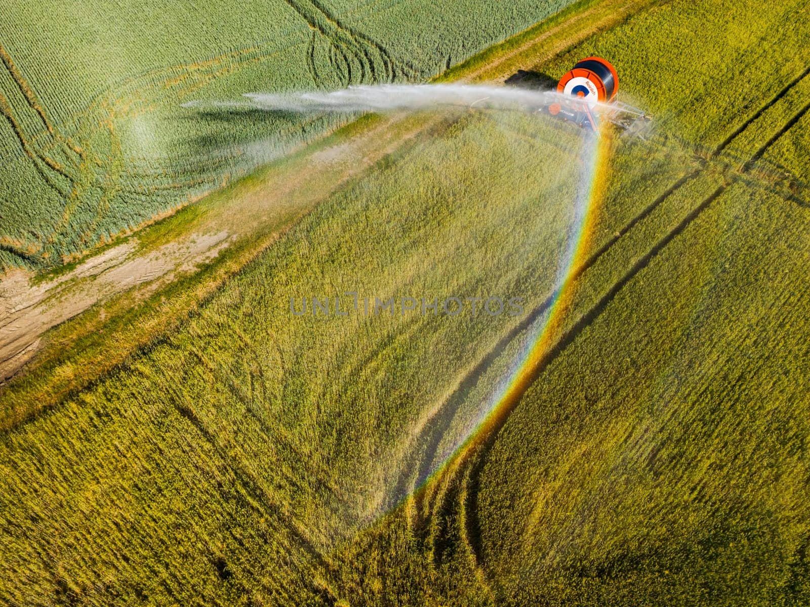 Irrigation system on a field with water jet and rainbow seen from above with a drone