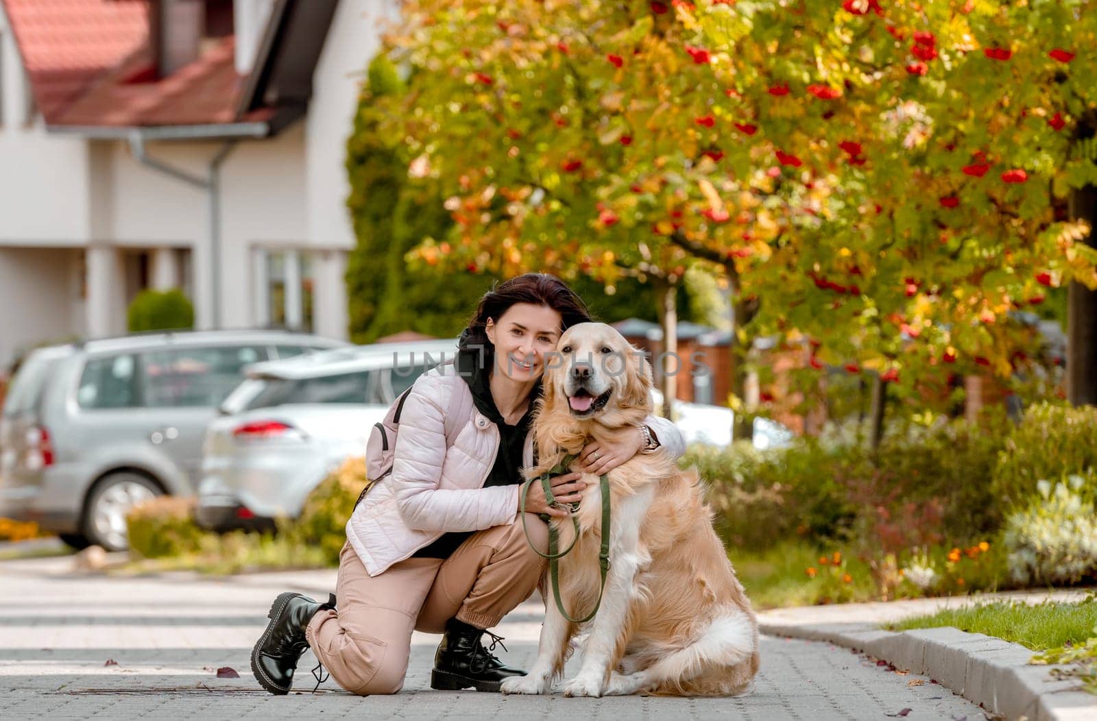 Preteen girl wear on golden retriever dog lace outdoors. Pretty woman with purebred pet doggy walking at autumn street