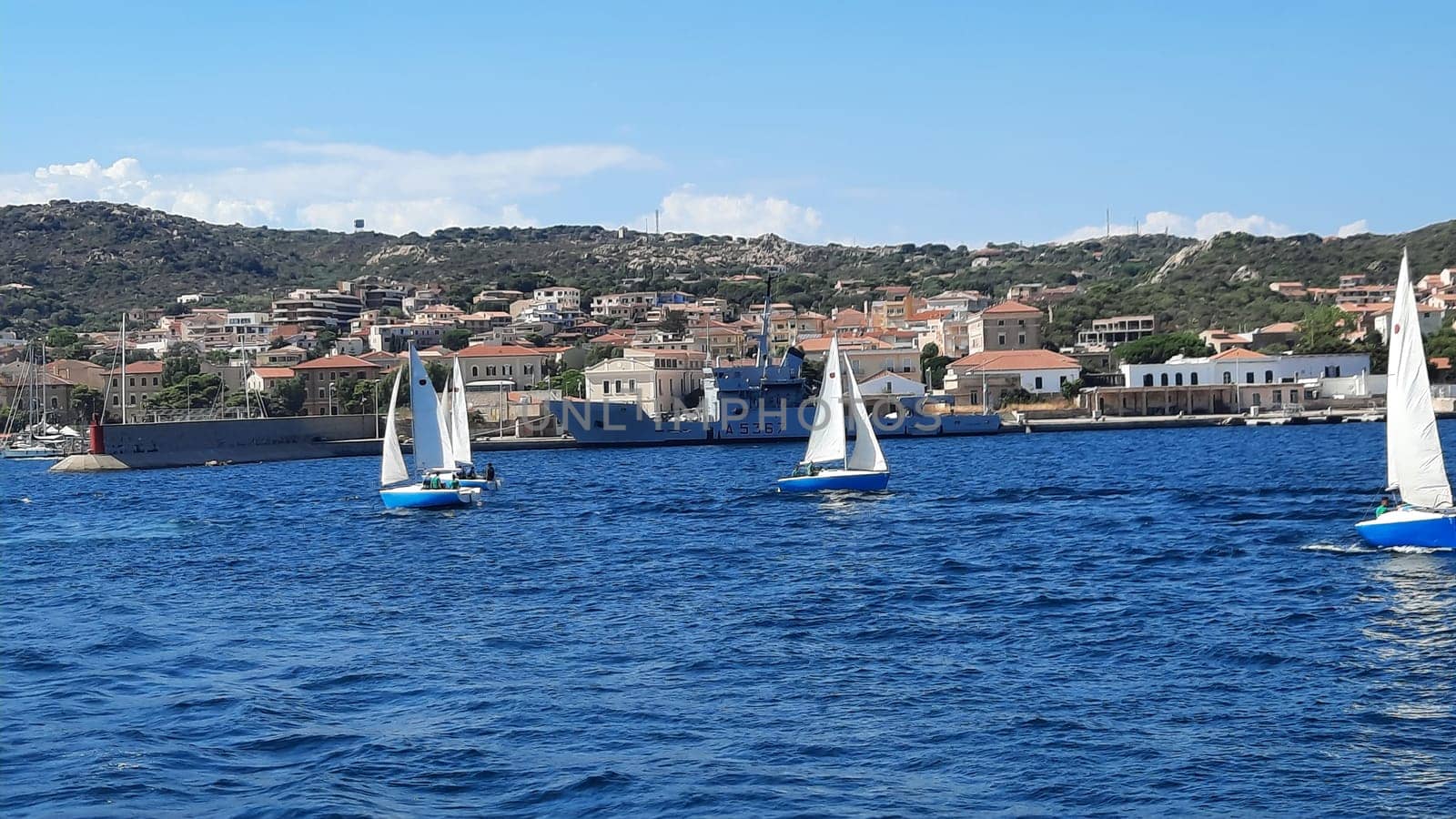 White yachts are anchored in a blue bay near Sardinia, Italy. Beautiful seascape with ships. A group of white yachts are moored in a sunny bay by Costin