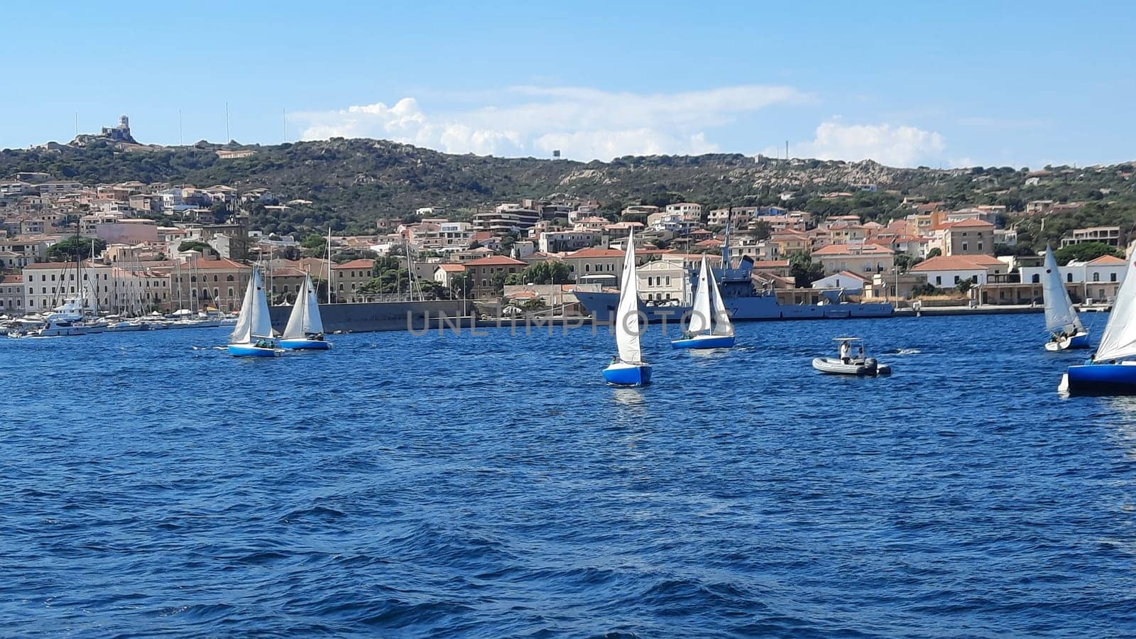 White yachts are anchored in a blue bay near Sardinia, Italy. Beautiful seascape with ships. A group of white yachts are moored in a sunny bay by Costin