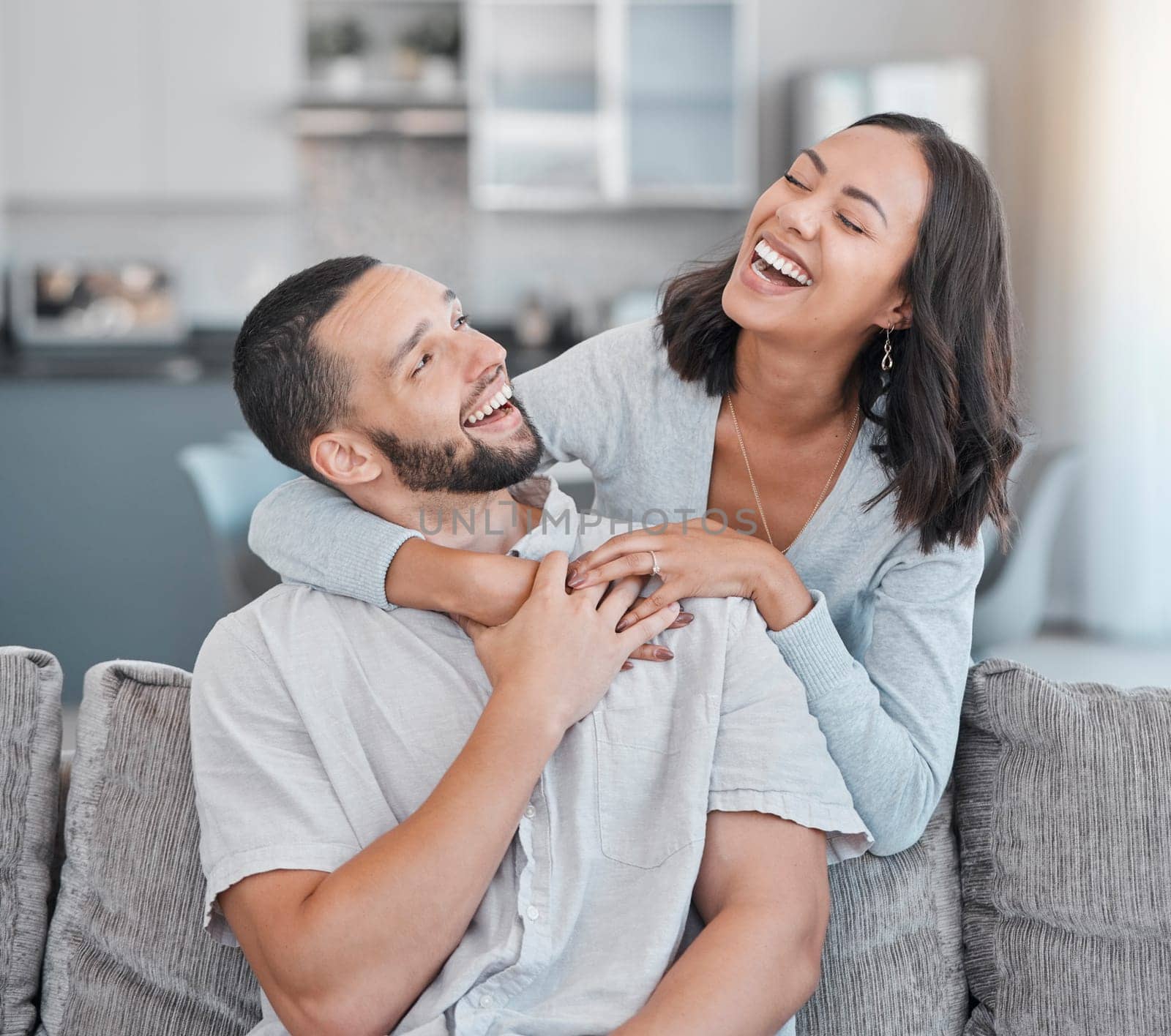 Couple relax on sofa, laugh and smile together with love, support and hug partner in living room of modern apartment home. Black woman, happy man and peace in lounge with wellness bonding on a couch.